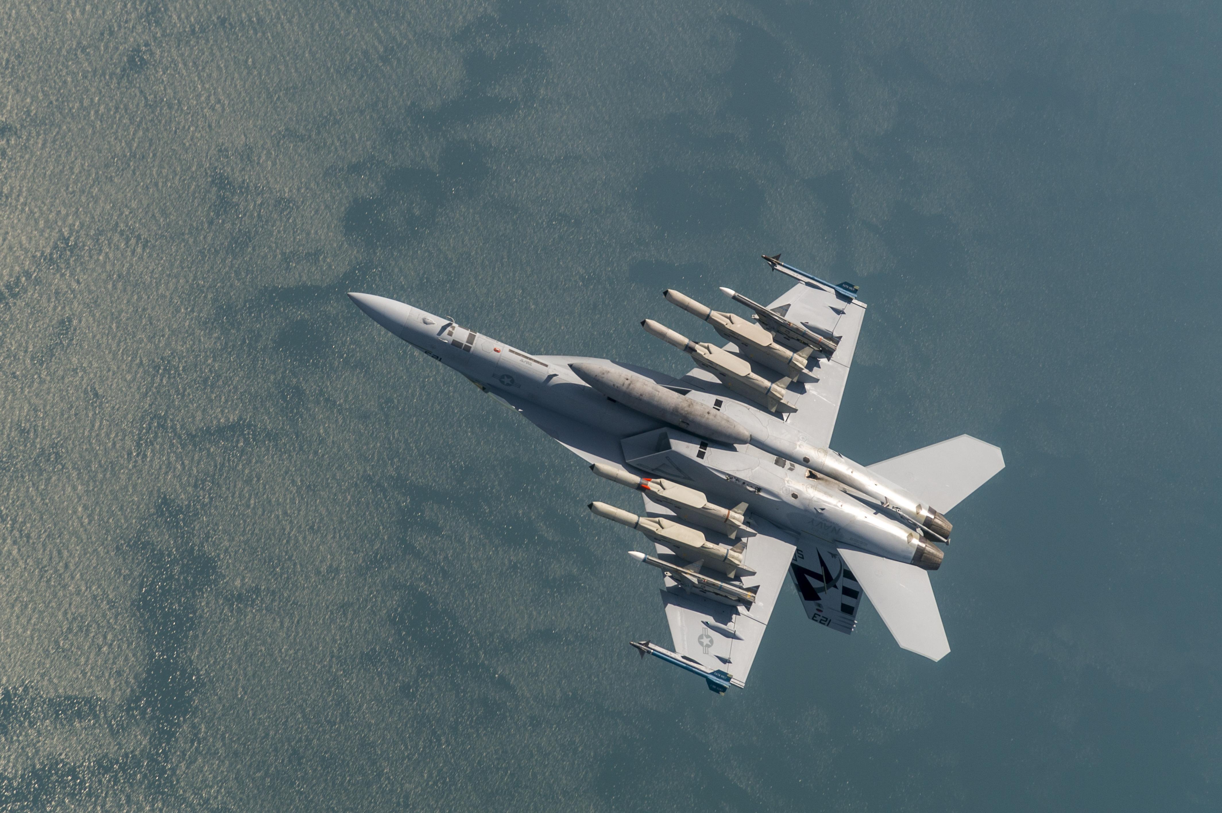 A weaponized F/A-18 flies over the Atlantic Ocean.