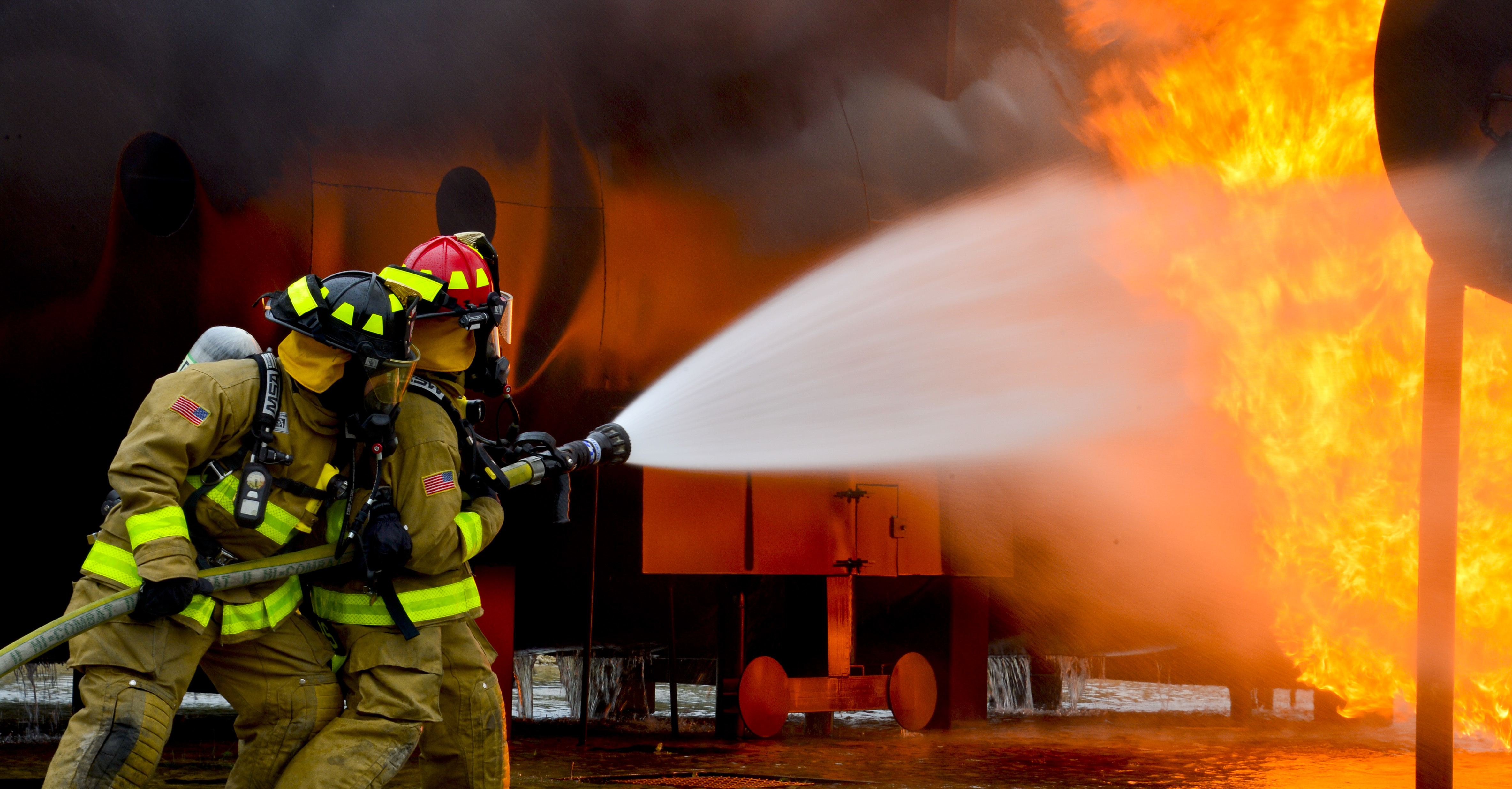 Firefighters from the 181st and the 317th Engineer Detachment spray water during an aircraft rescue and firefighting fire burn.