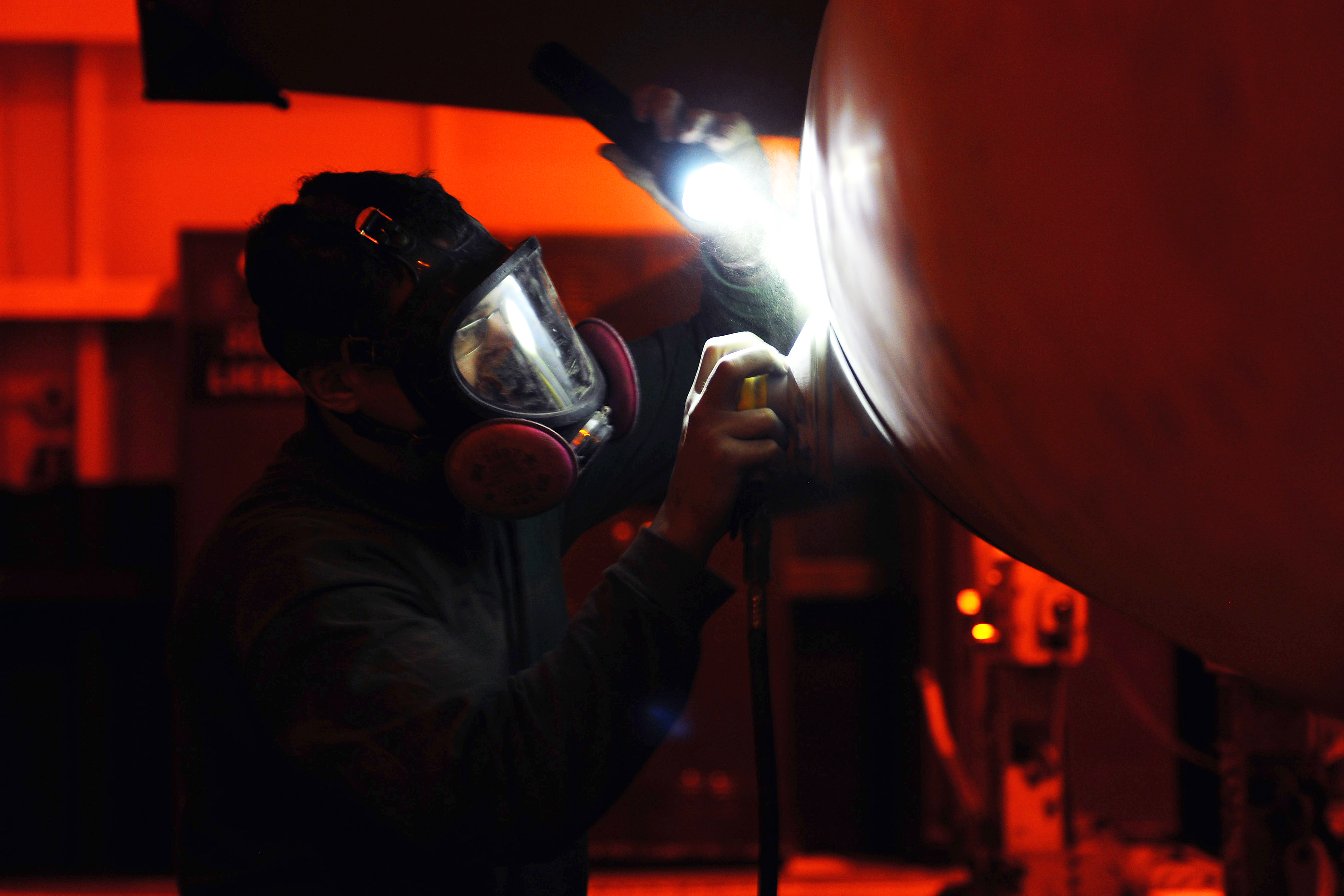 U.S. Navy Seaman performs corrosion prevention maintenance on an F/A-18F Super Hornet 