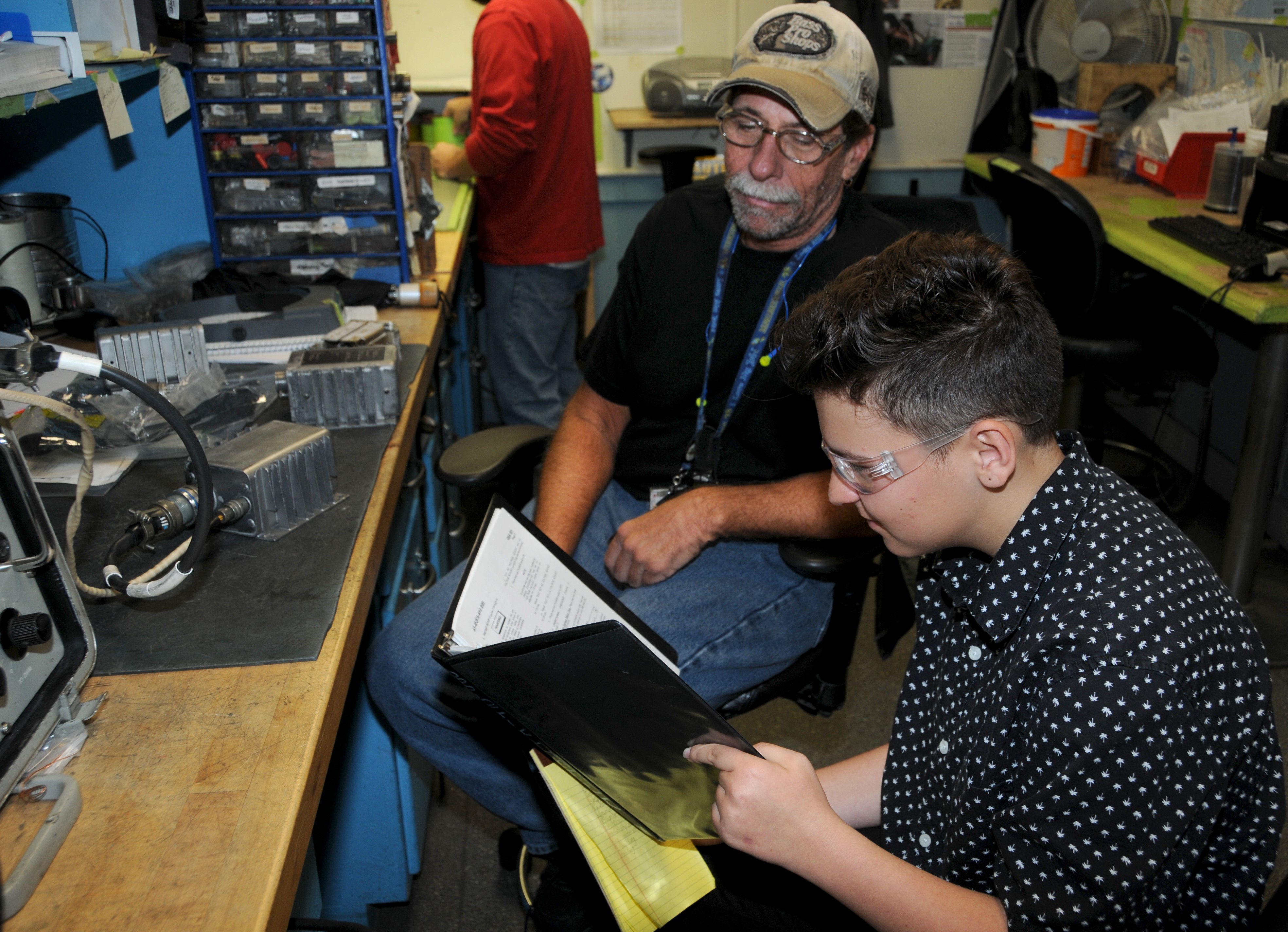 High school students looks at technical data manual for aircraft component