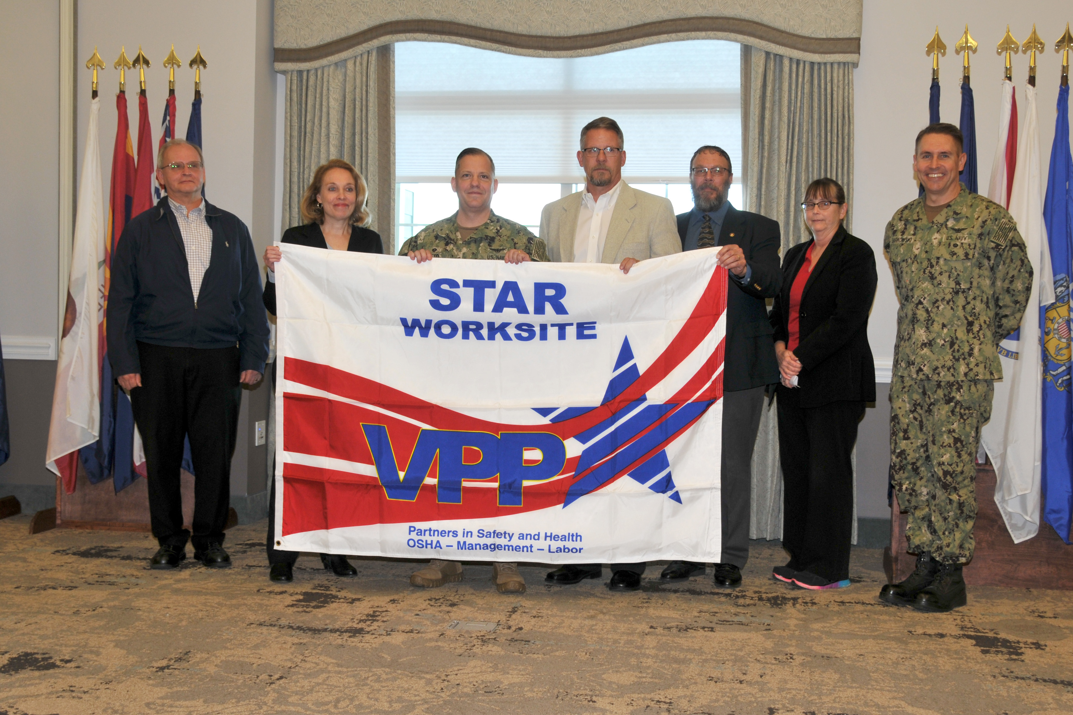 FRCE leadership poses with the VPP Star Worksite flag.
