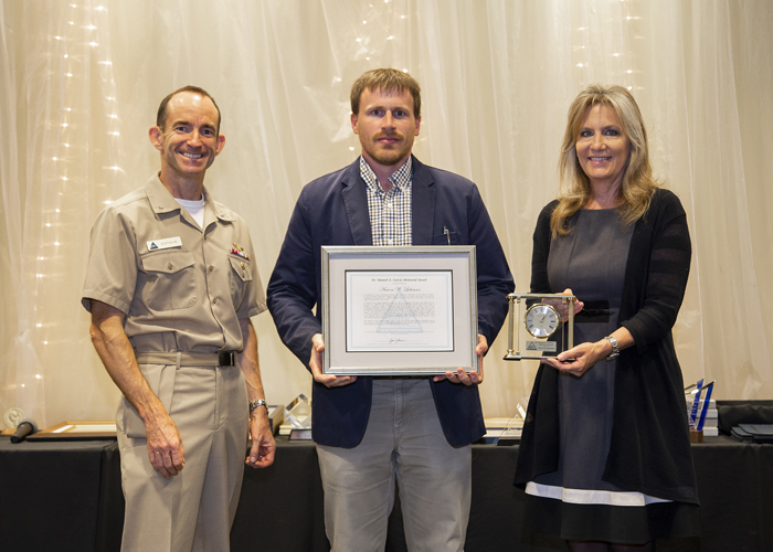 Aaron Lehman accepts the Dr. Manuel A. Garcia Memorial Award from Rear Adm. Scott Dillon, NAWCWD commander, and Joan Johnson, NAWCWD executive director, during the 2019 Honorary Awards Ceremony at China Lake on June 25. (U.S. Navy photo by Ryan Smith)