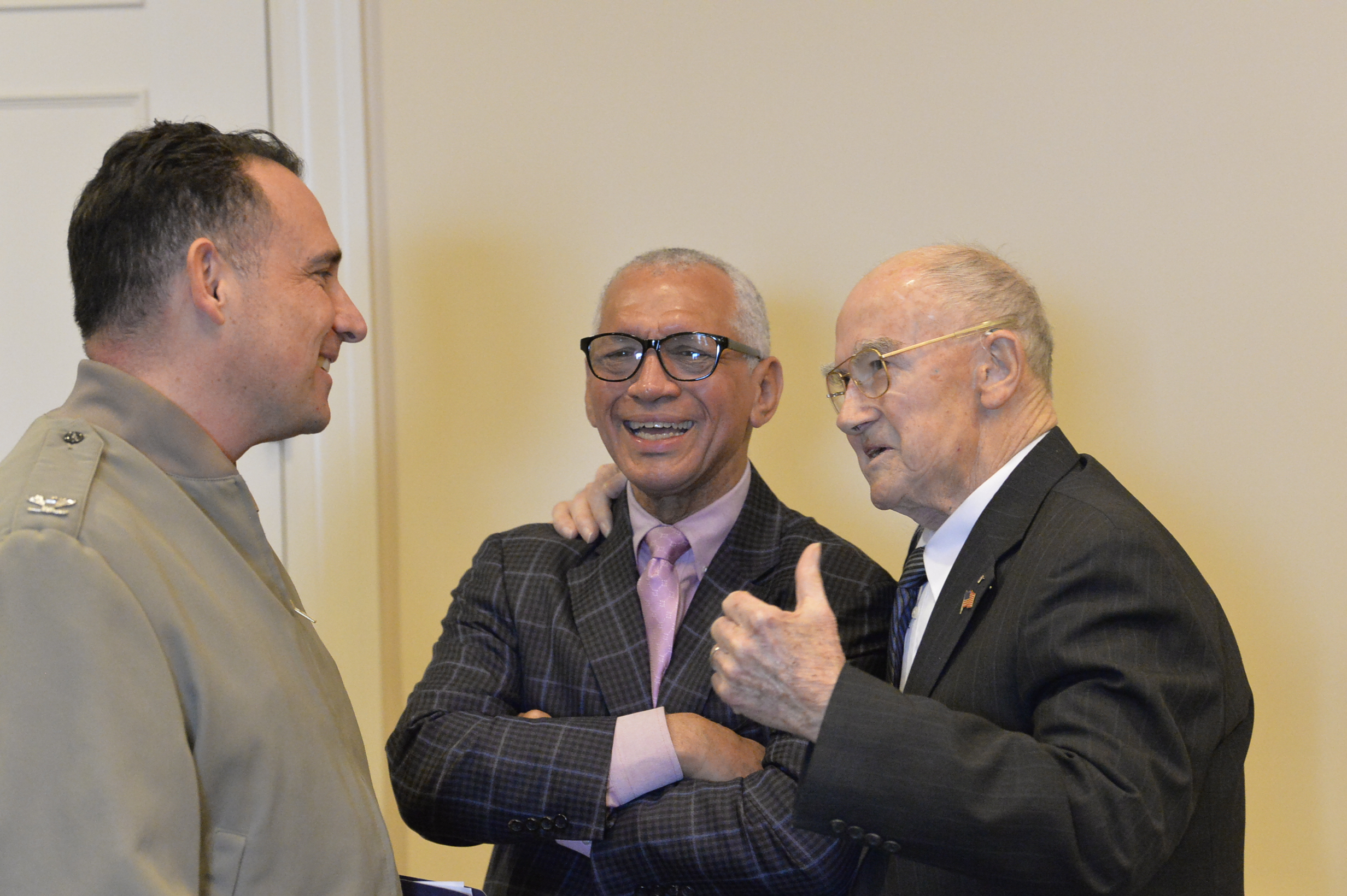 Naval Test Wing Atlantic commander, Col. Richard E. Marigliano, left, and retired Maj. Gen. Charles Bolden, former astronaut and NASA administrator, center, laugh as retired Lt. Cmdr. Harry Errington recalls a story prior to the air wing’s annual awards luncheon for 2019 honorees.