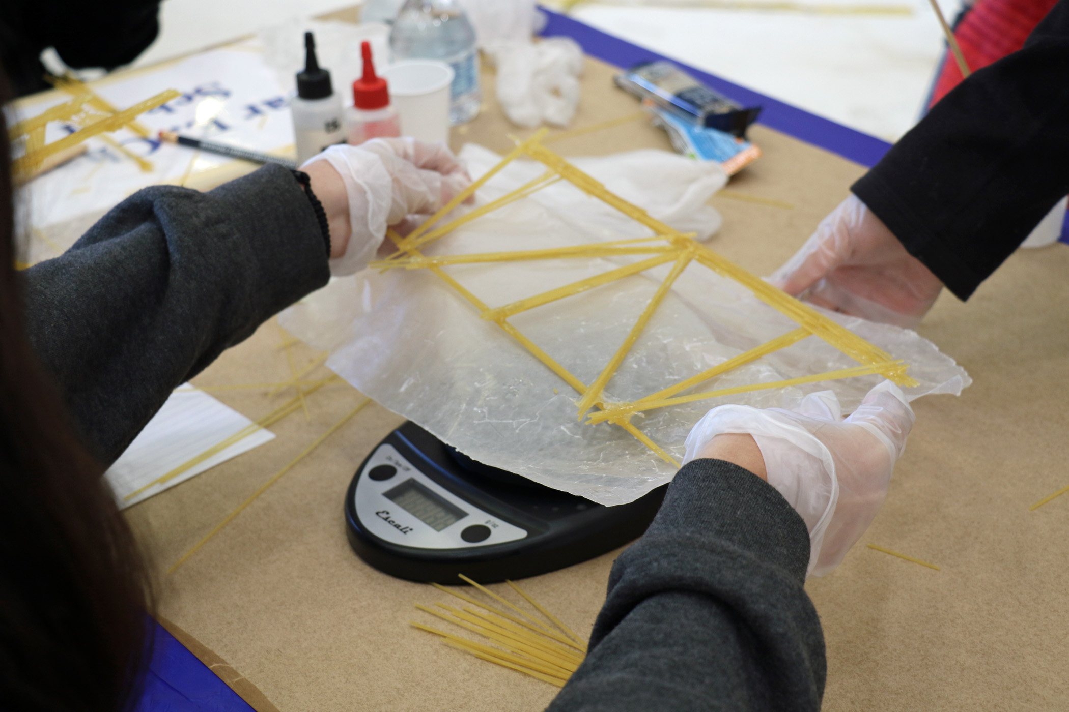 Students participating in the annual Tri-Warfare Center STEM Challenge in Point Mugu, California, on Feb. 20 weigh their spaghetti bridge, which could not weigh more than 50 grams. (U.S. Navy photo by Kimberly Brown)