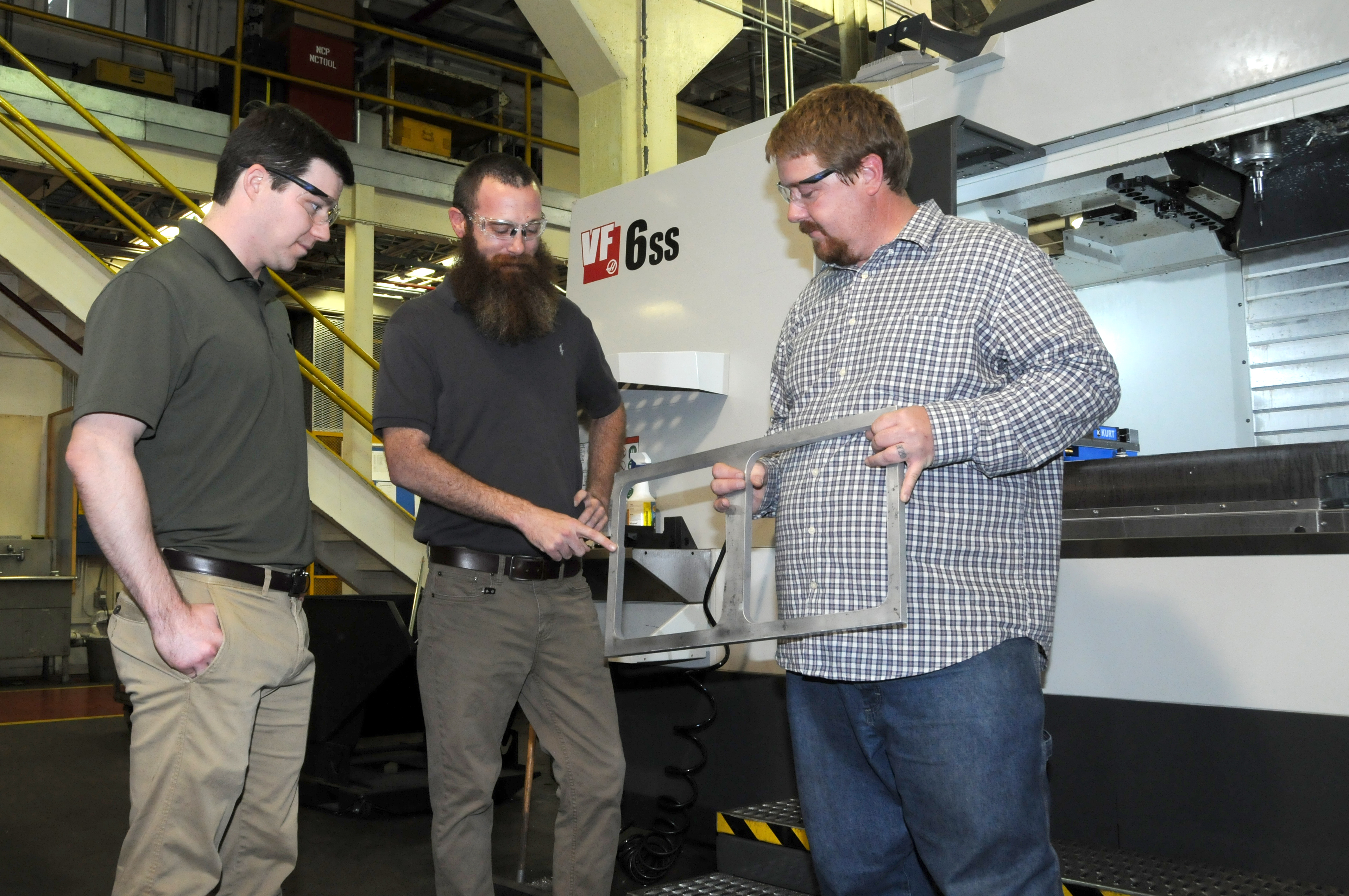 Men discuss metal bracket used in component production