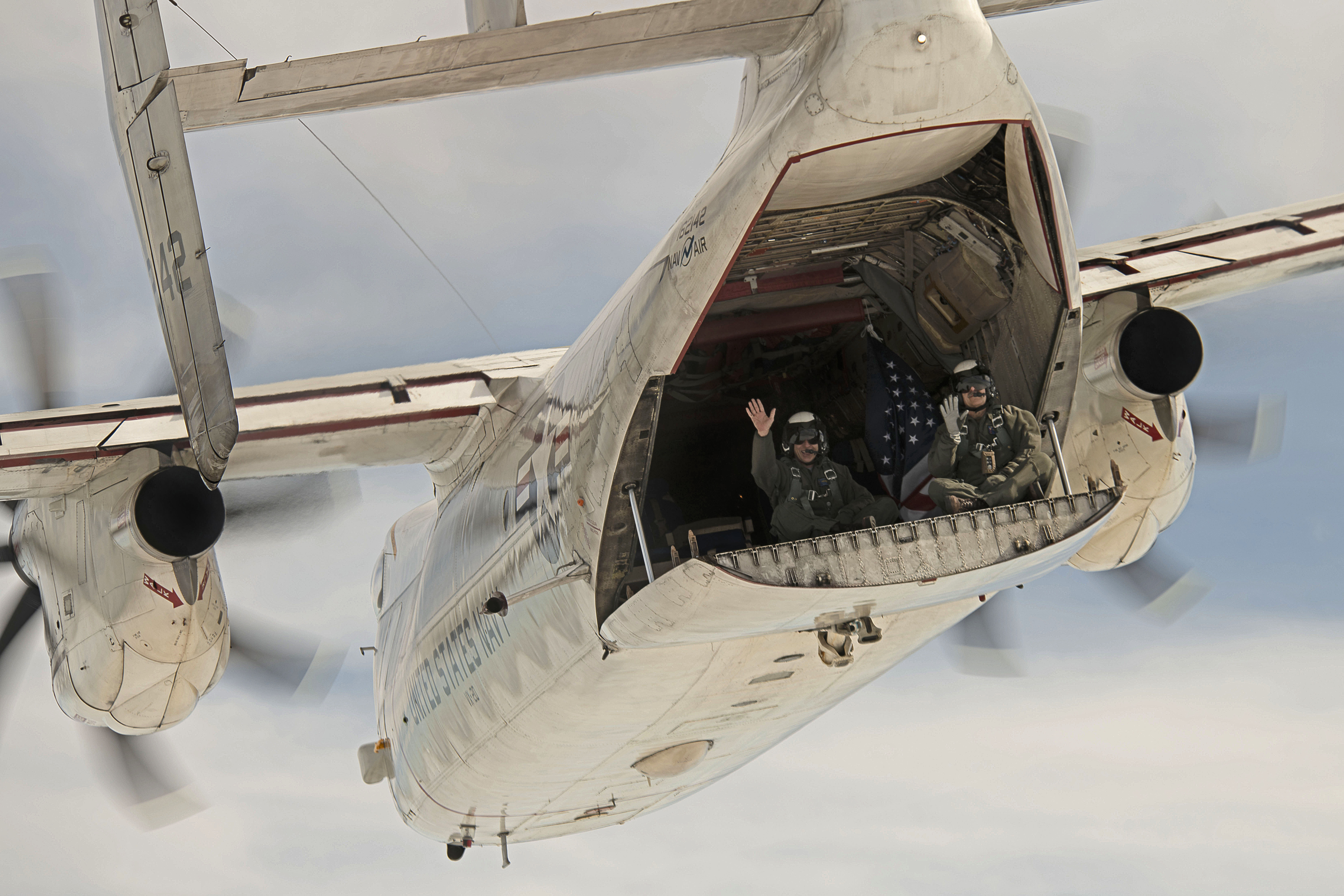 Long-time C-2A aircrew Jim Fortini, left, and Al Griffin wave from the back of C-2A Greyhound BuNo 162142 on its last flight, which took place last month. The aircraft, which has been flying with VX-20 for nearly 30 years, will be retired to the Patuxent River Naval Air Museum. (U.S. Navy photo by Erik Hildebrandt)