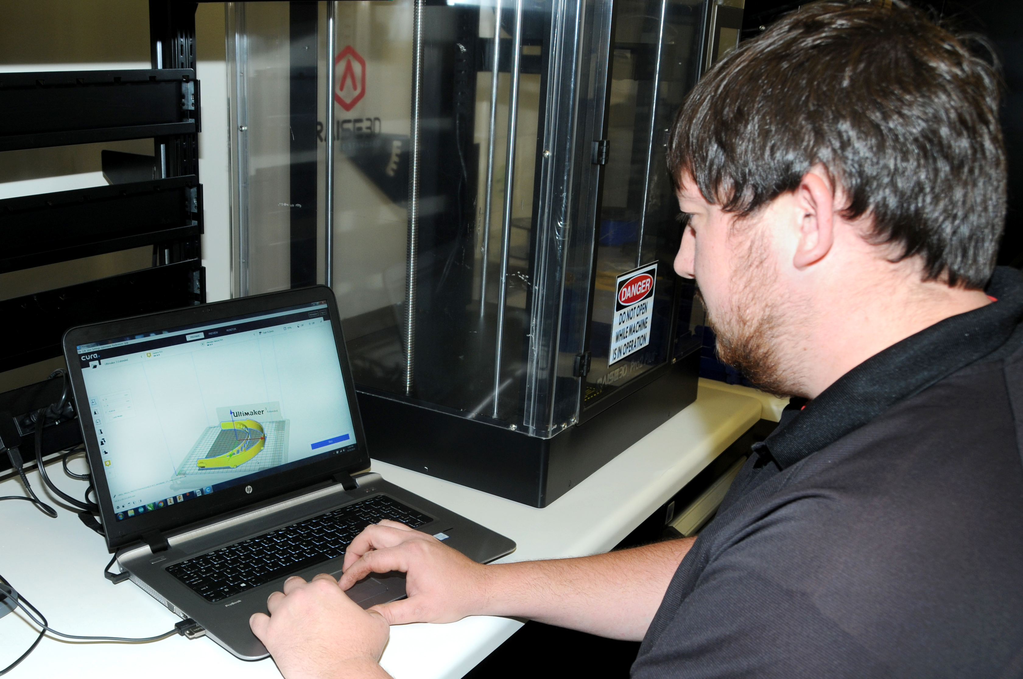 Innovation lead Randall Lewis uses a computer-aided design file to 3D print face shield headbands