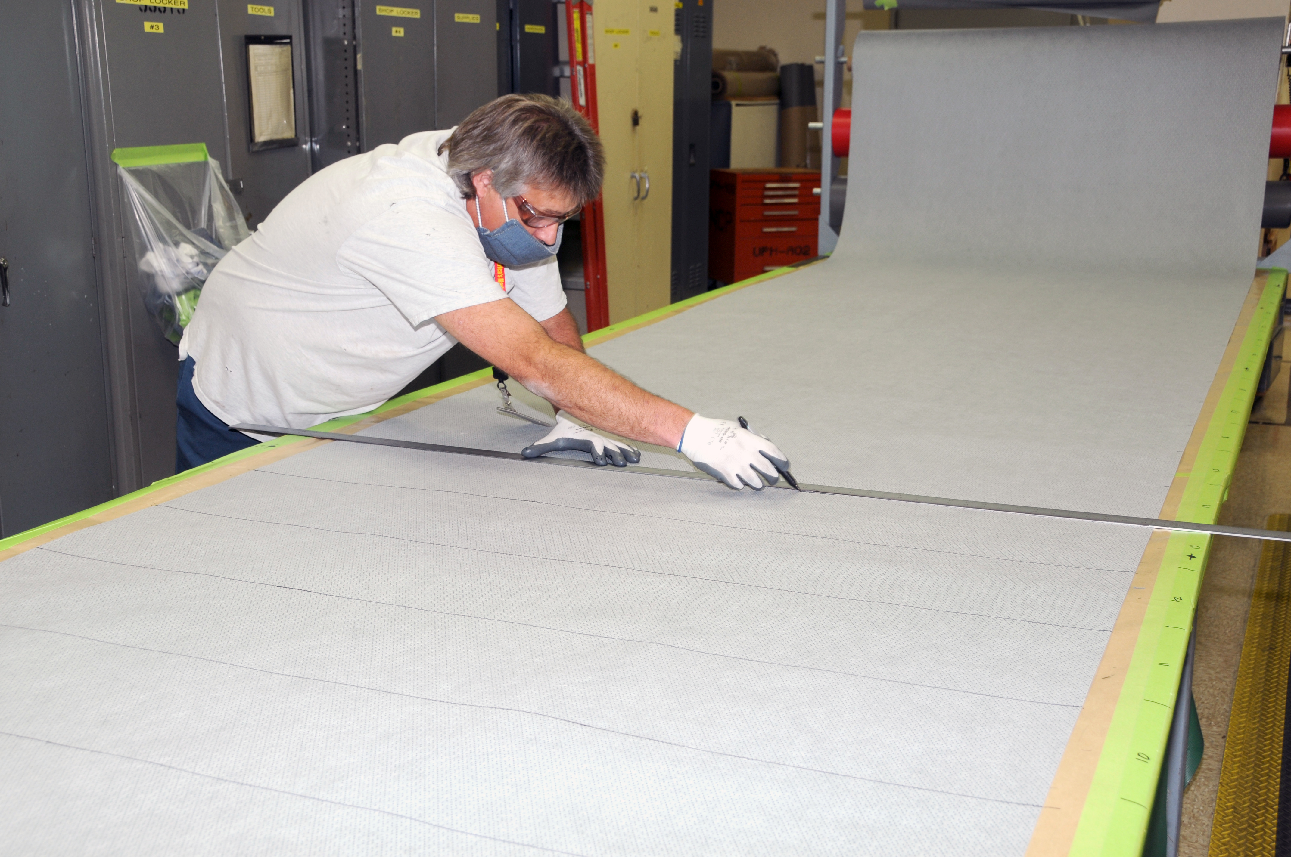 Man uses straight edge to cut fabric for cloth face coverings