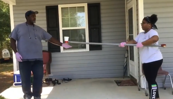 Girl passes a drink to an adult using a tool she invented during educational challenge