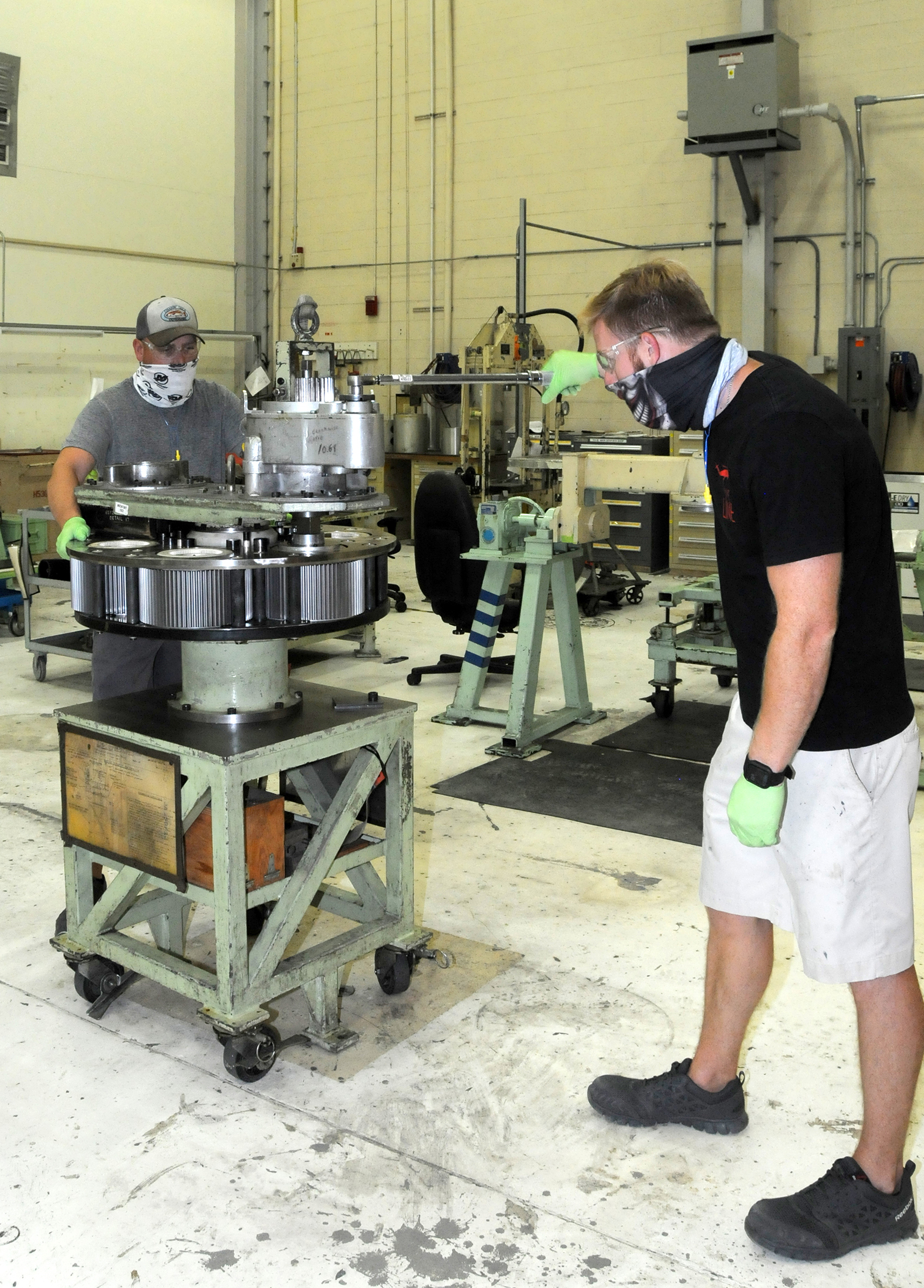 Two aircraft mechanics torque pinion nuts on first-stage planetary gear