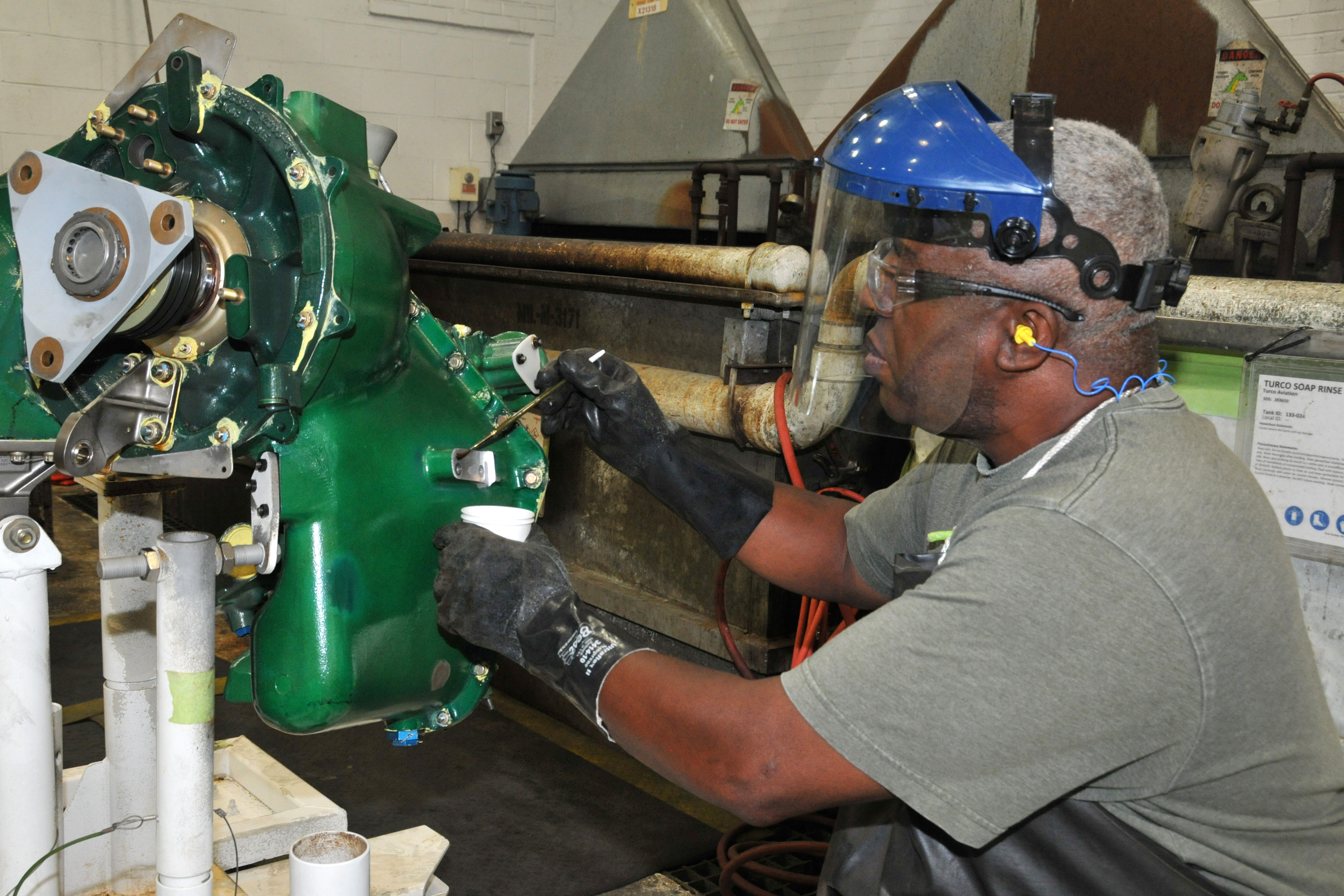 Painter applies anti-corrosion coating to aircraft part.