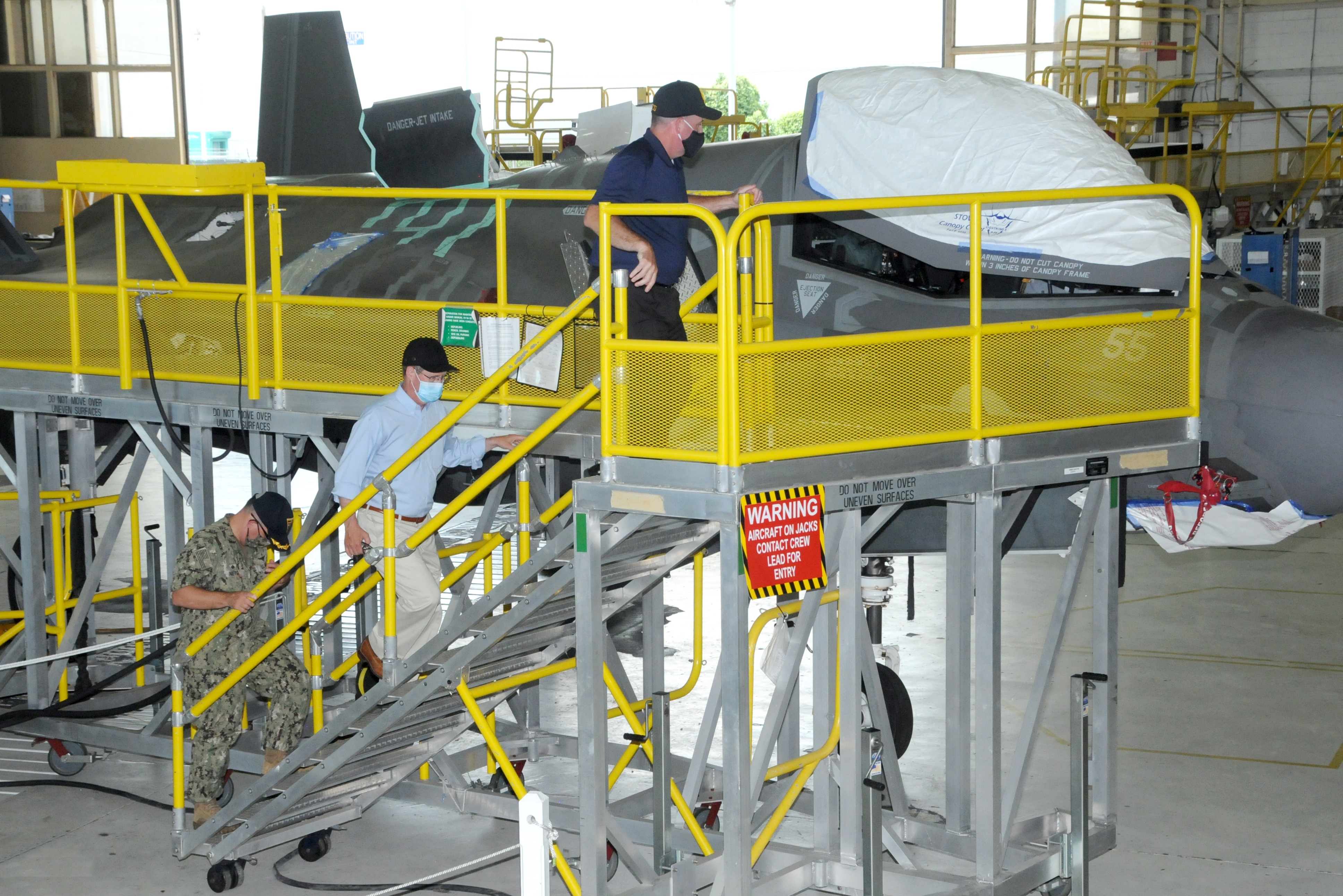 Three men climb stand to view F-35 aircraft