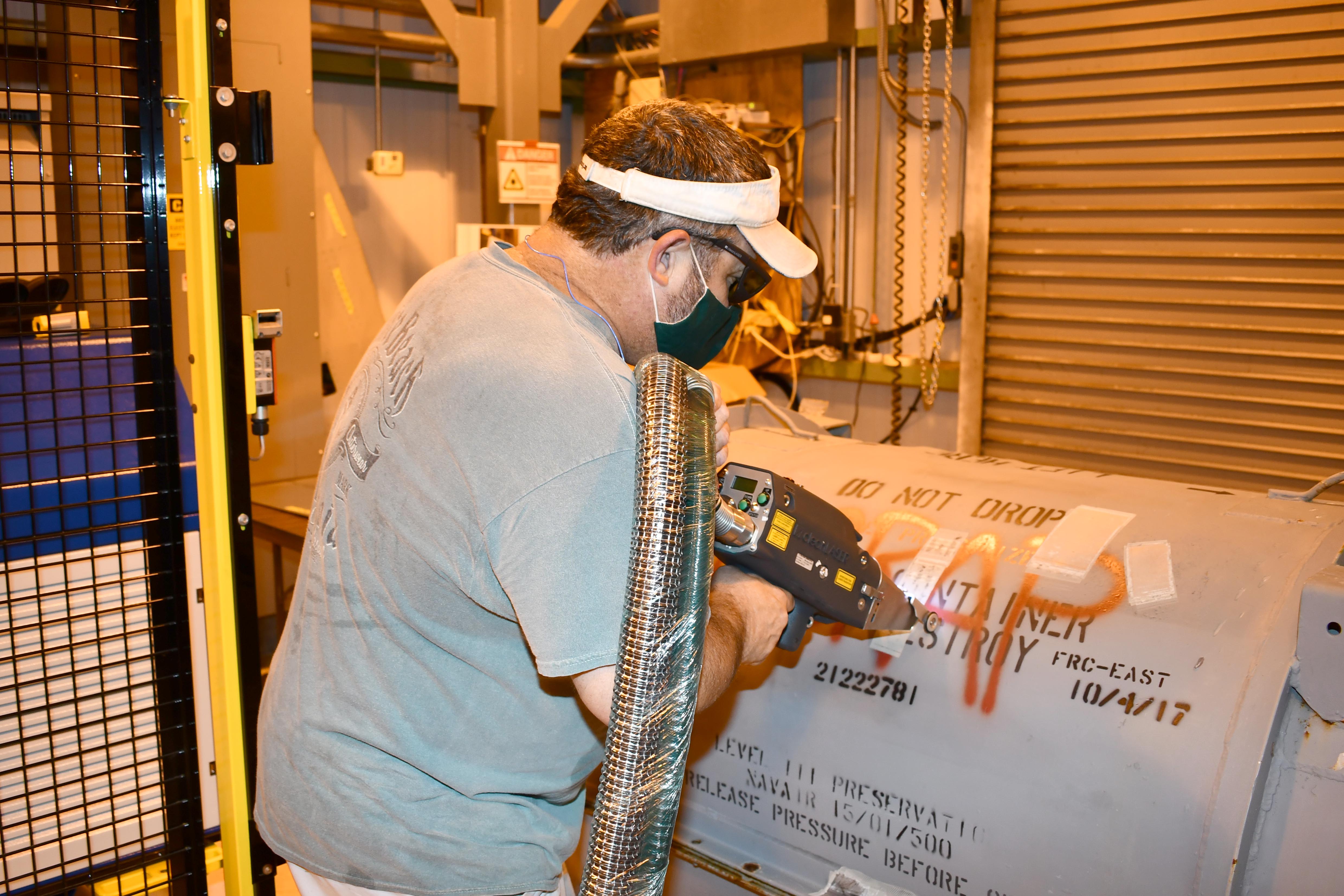 Worker users laser to clean container