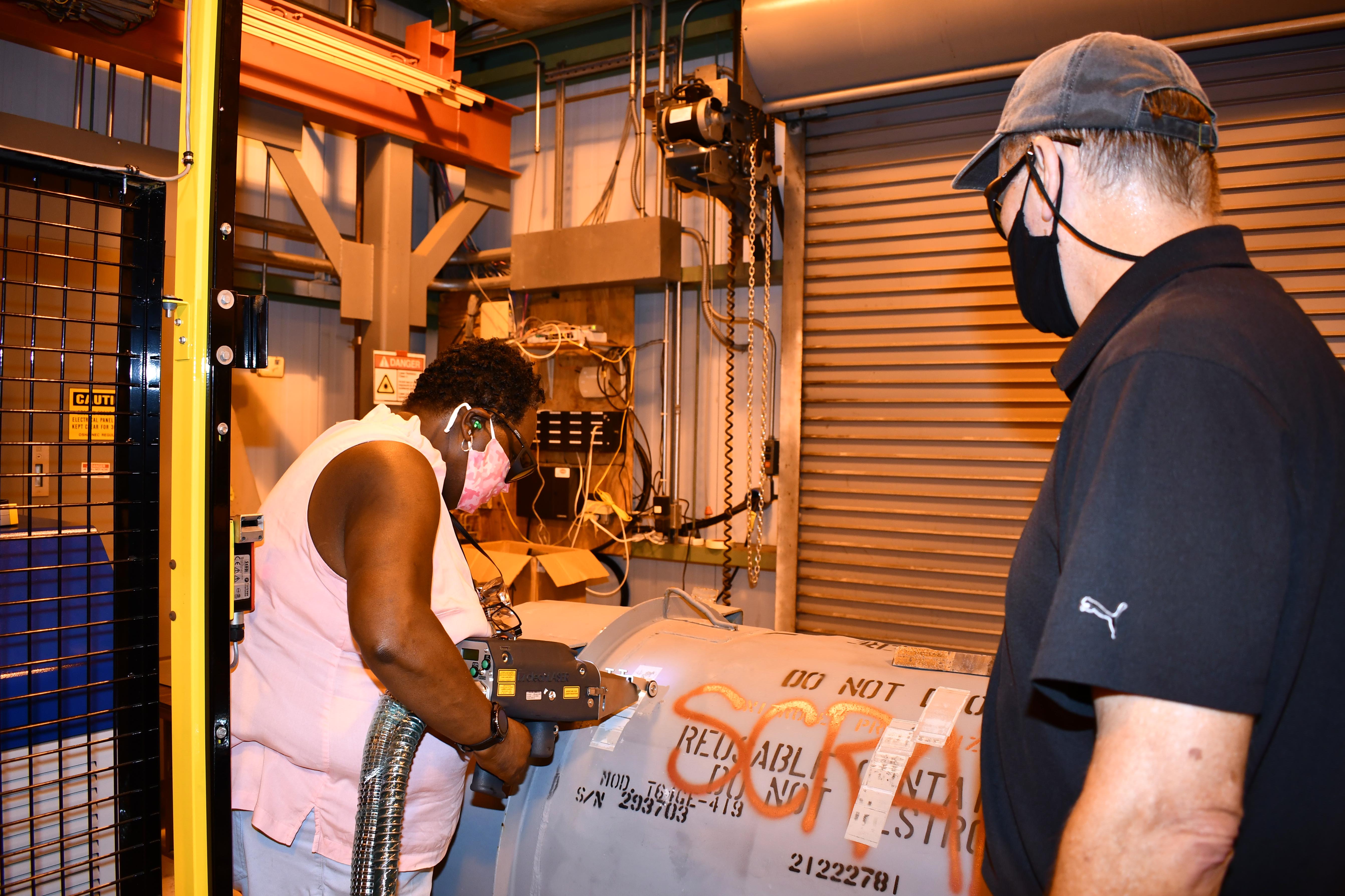 Worker uses laser while trainer watches
