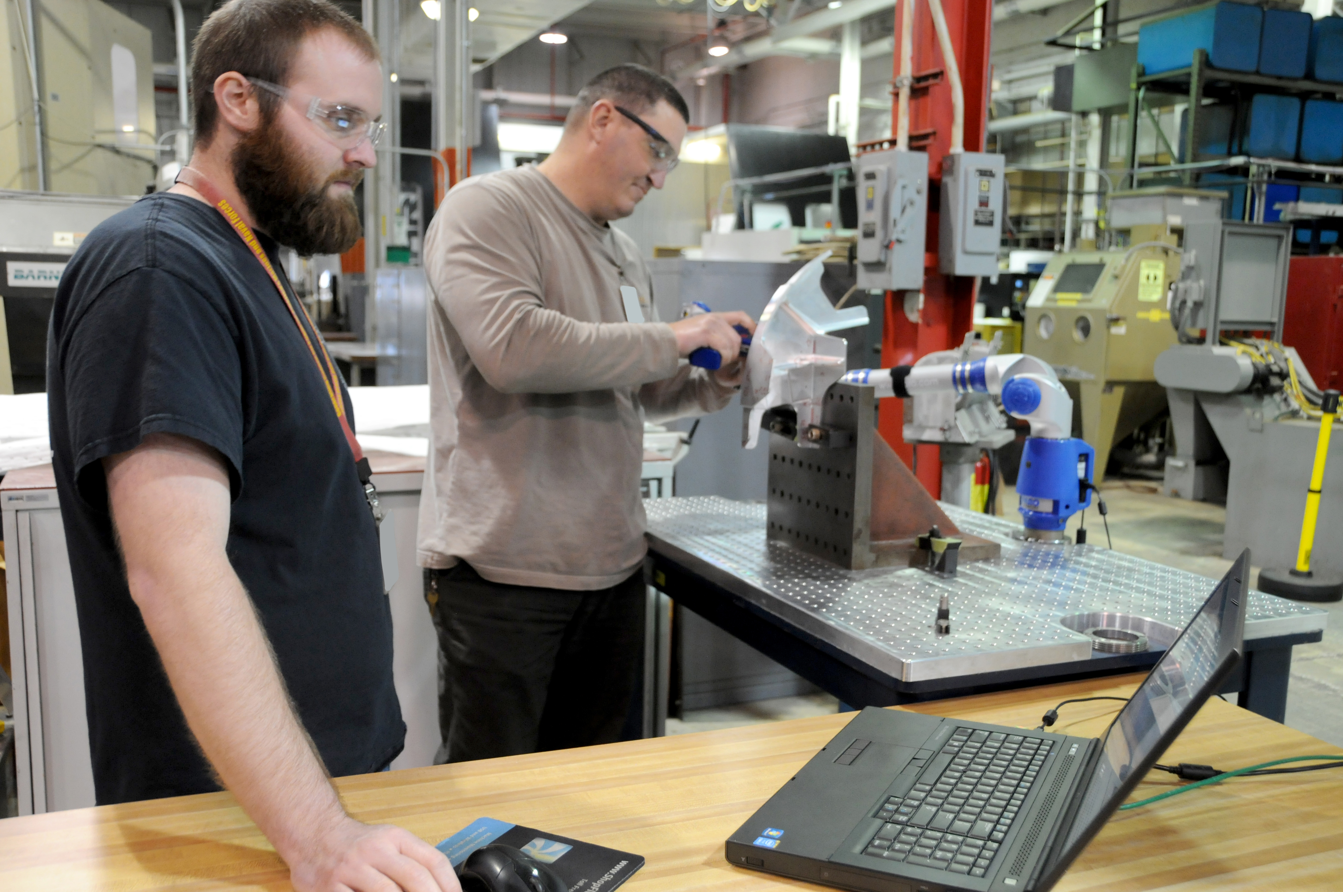 FRCE machinists measure a 522 fitting using a FaroArm