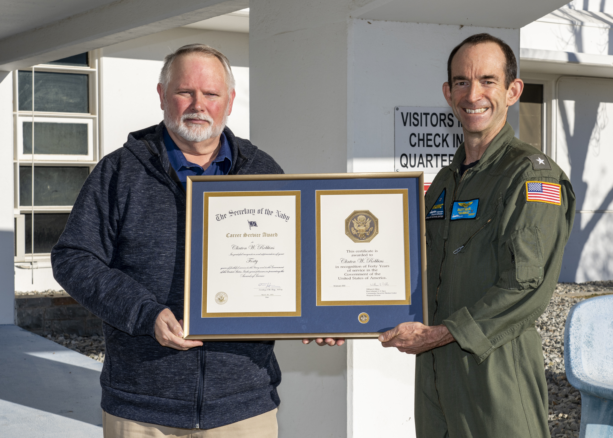 Clint Robbins poses with Rear Adm. Scott Dillon in front of the headquarters building in China Lake after receiving a 40-year length-of-service award on Jan. 6. (U.S. Navy photo by Ryan Smith)