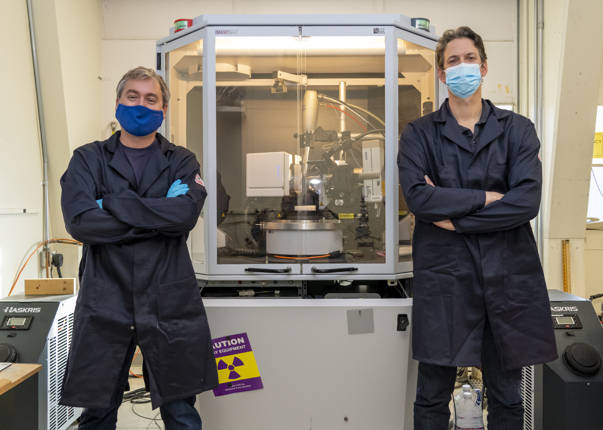 Dr. Randall McClain, left, and Dr. Ben Harvey stand in front of a single crystal X-ray diffractometer, which is used to determine the chemical structure of molecules. (U.S. Navy photo by Ryan Smith)