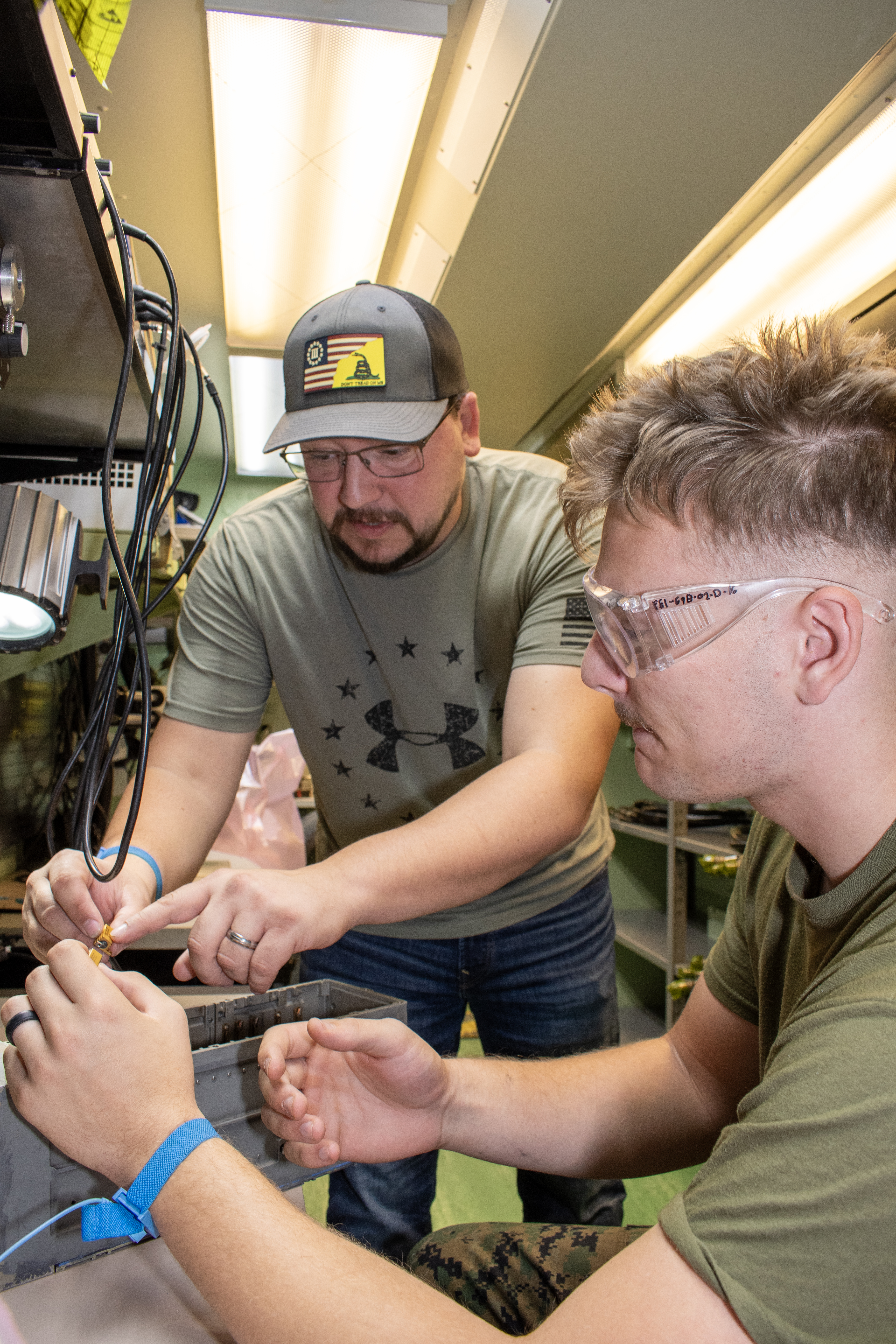 Civilian electronics integrated system mechanic explains F/A-18 Hornet circuit breaker panel to Marine.