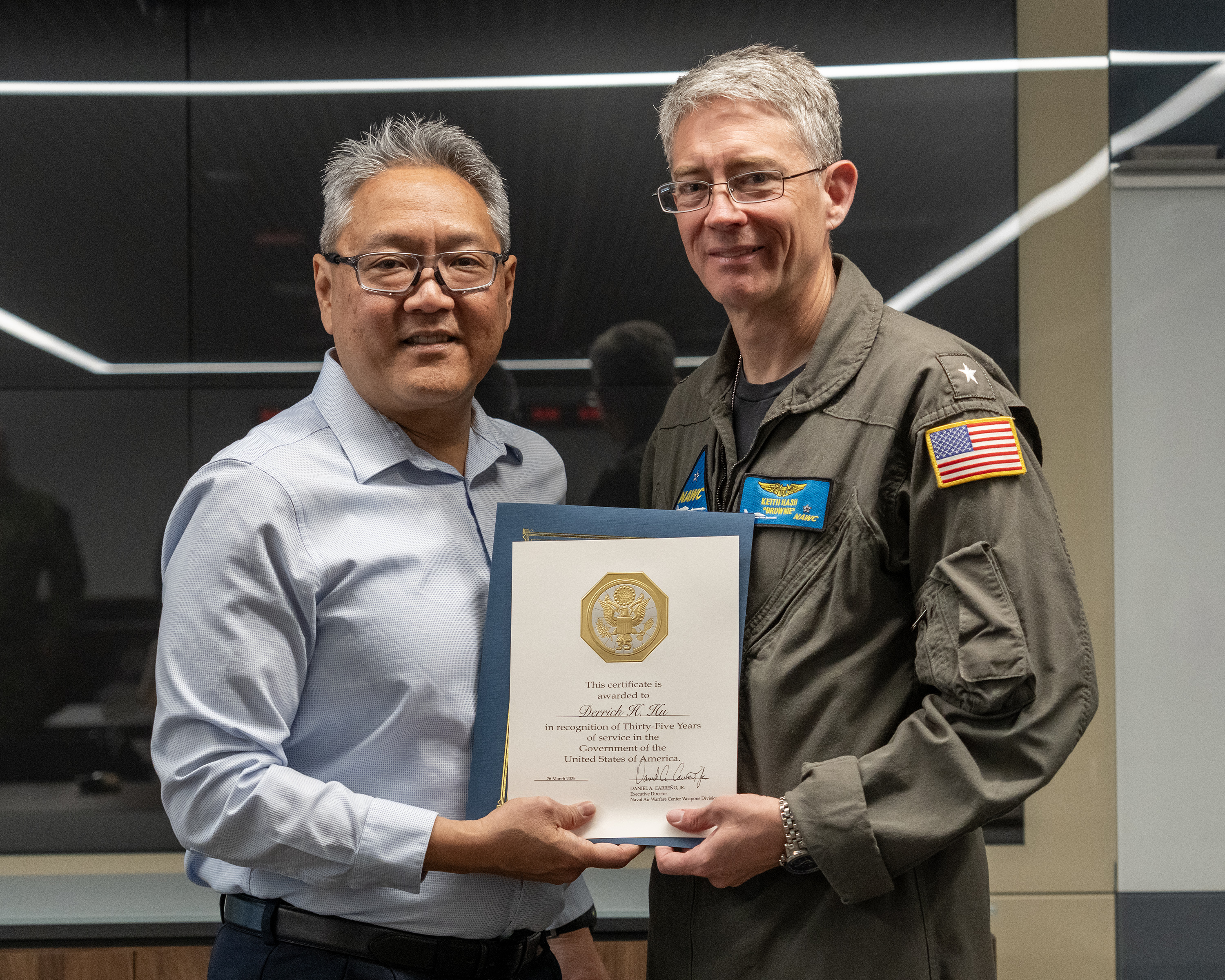 Derrick Hu, director of the Office of Small Business Programs at Naval Air Warfare Center Weapons Division, poses with Rear Adm. Keith Hash, commander of Naval Air Warfare Center Weapons Division, after receiving his 35-year Length of Service award during a ceremony in China Lake, California. Hu’s career spans multiple roles and demonstrates unwavering dedication to supporting small businesses and the warfighter. (U.S. Navy photo by Ryan Smith)
