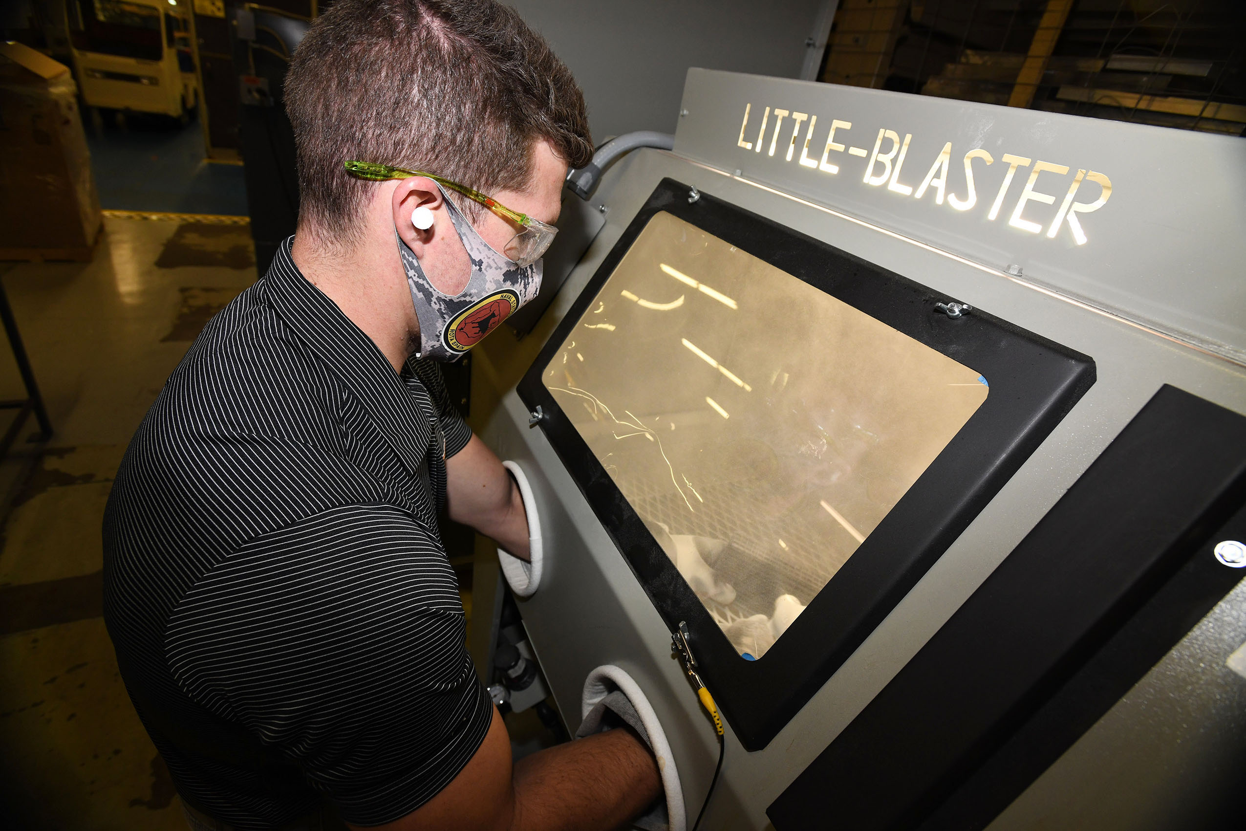 Fleet Readiness Center Southeast (FRCSE) Mechanical Engineer, Evan Grambling, utilizes a manual glass bead blaster as part of the processing procedures involved in the 3D printing of nasopharyngeal swabs. 