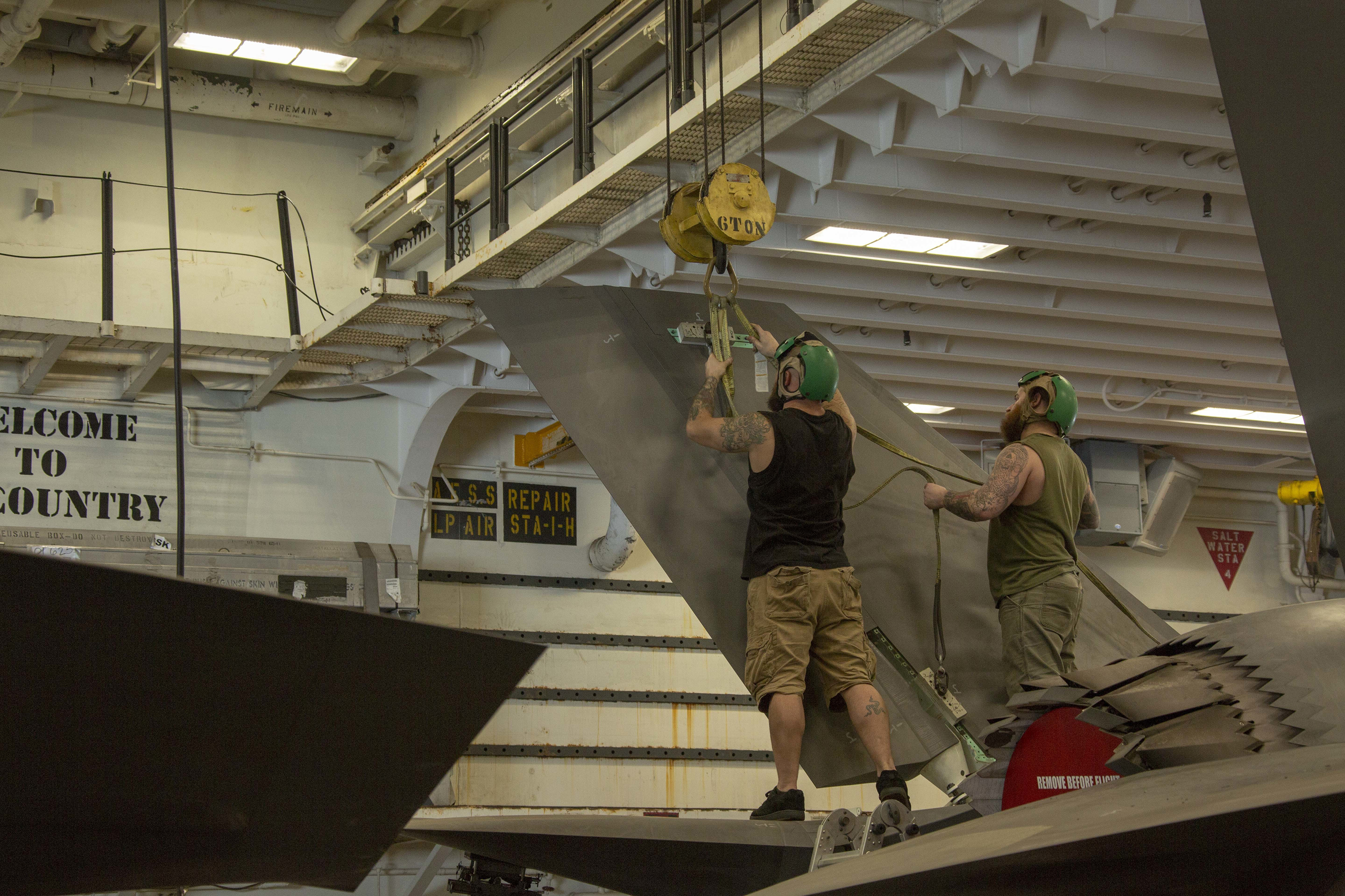 Two aircraft mechanics perform repairs on F-35B