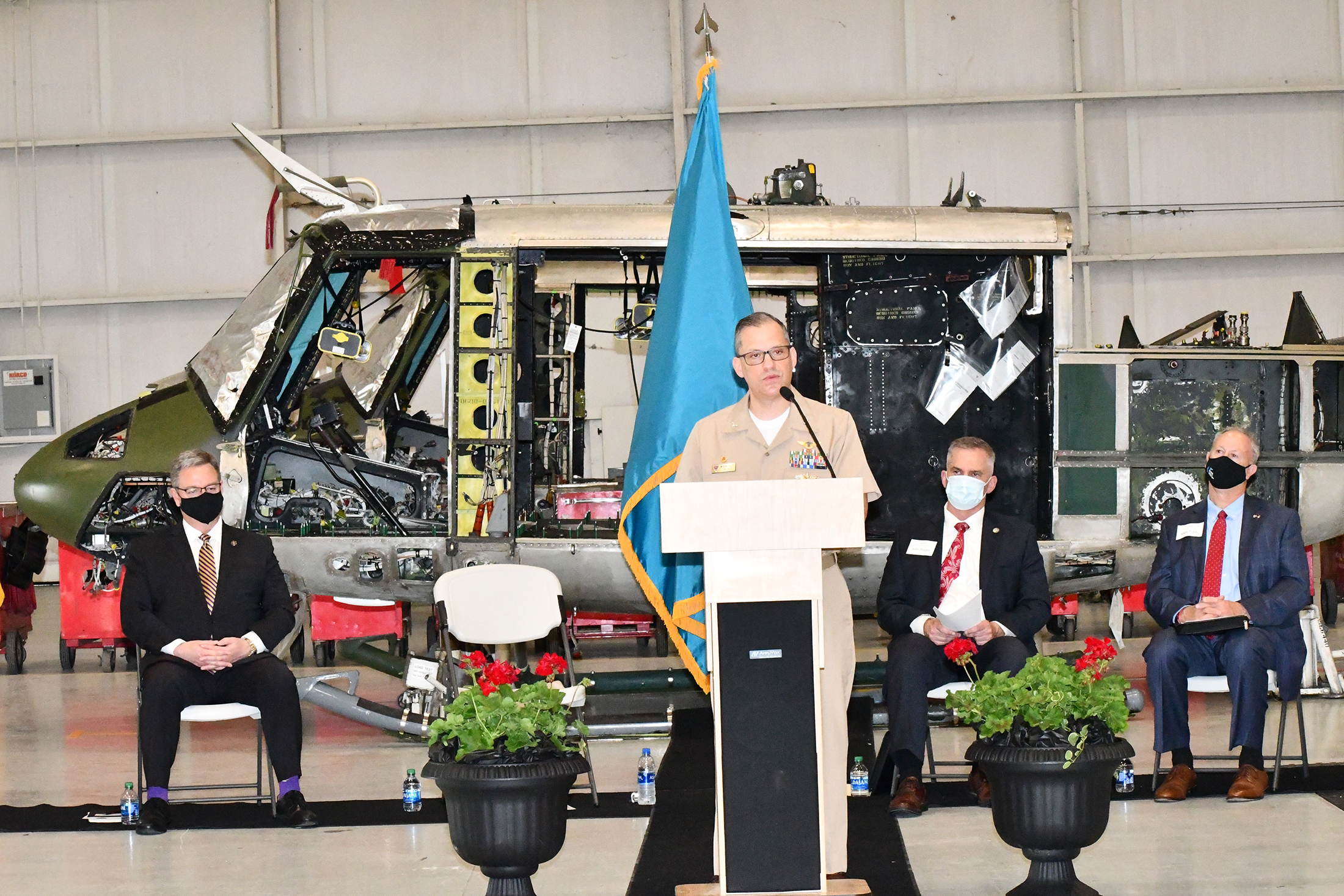 Navy captain and local dignitaries in front of H-1 helicopter airframe