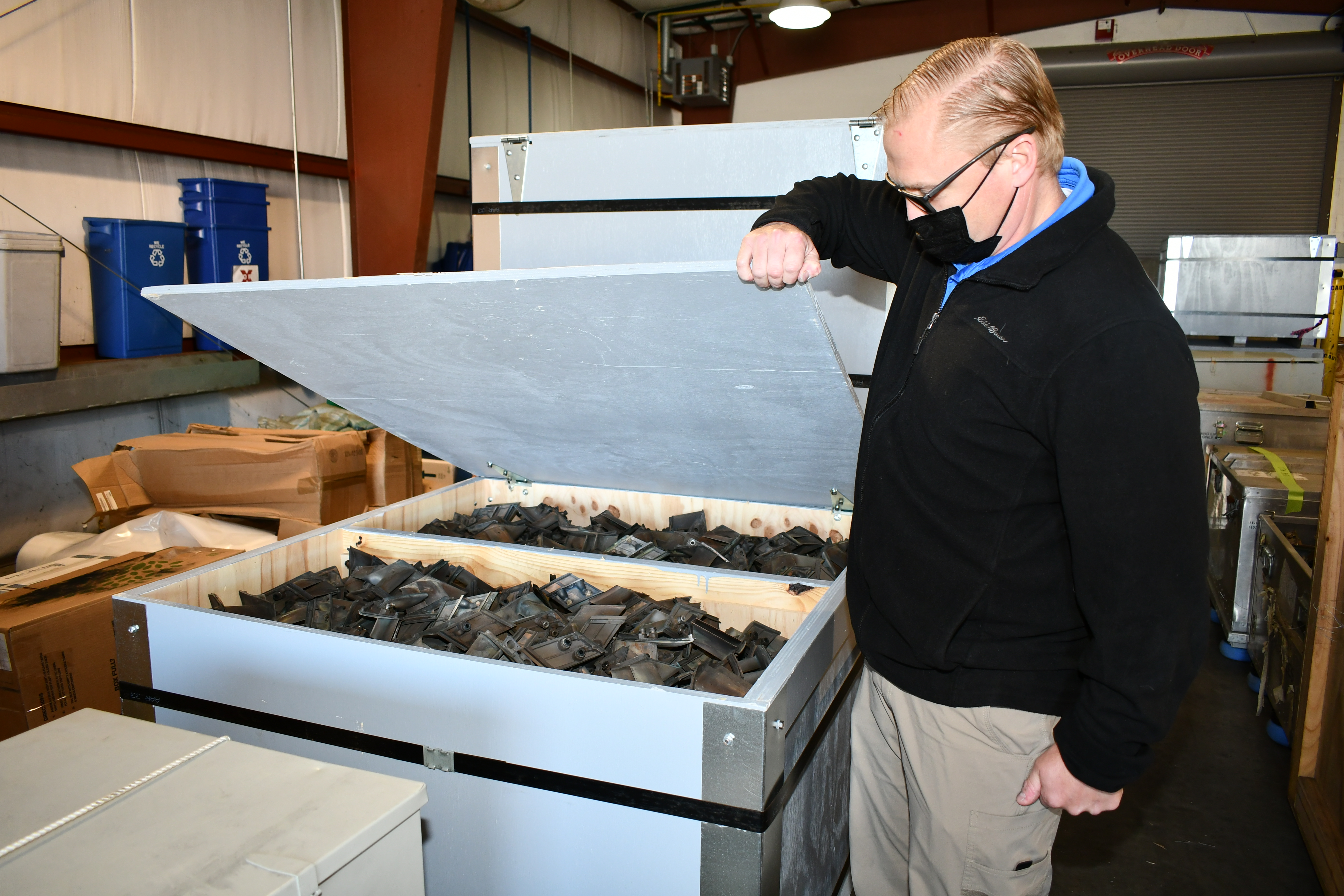 Man displays scrap parts in crate