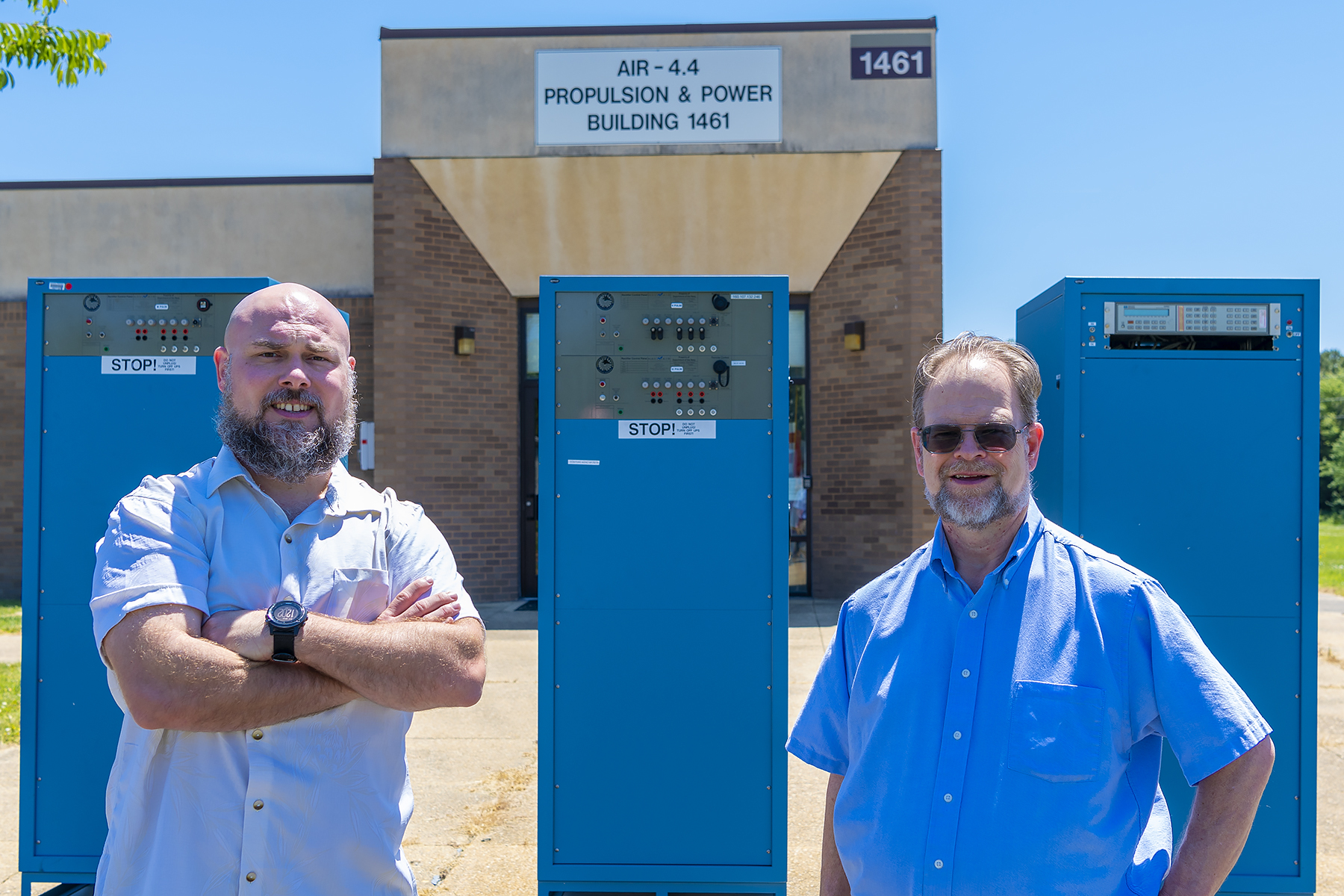 Senior Electrical Engineer Joshua Masters, left, and F-18 Electrical Subsystem Integrated Product Team  Lead Charles Singer stand in front of the computer-programmable power testing system they and other NAWCAD engineers invented to reduce the time required to test the avionics systems of the Navy's F/A-18 Hornets. The team, which received a patent for their invention, was recently recognized for their accomplishments in a virtual ceremony along with other patent awardees.