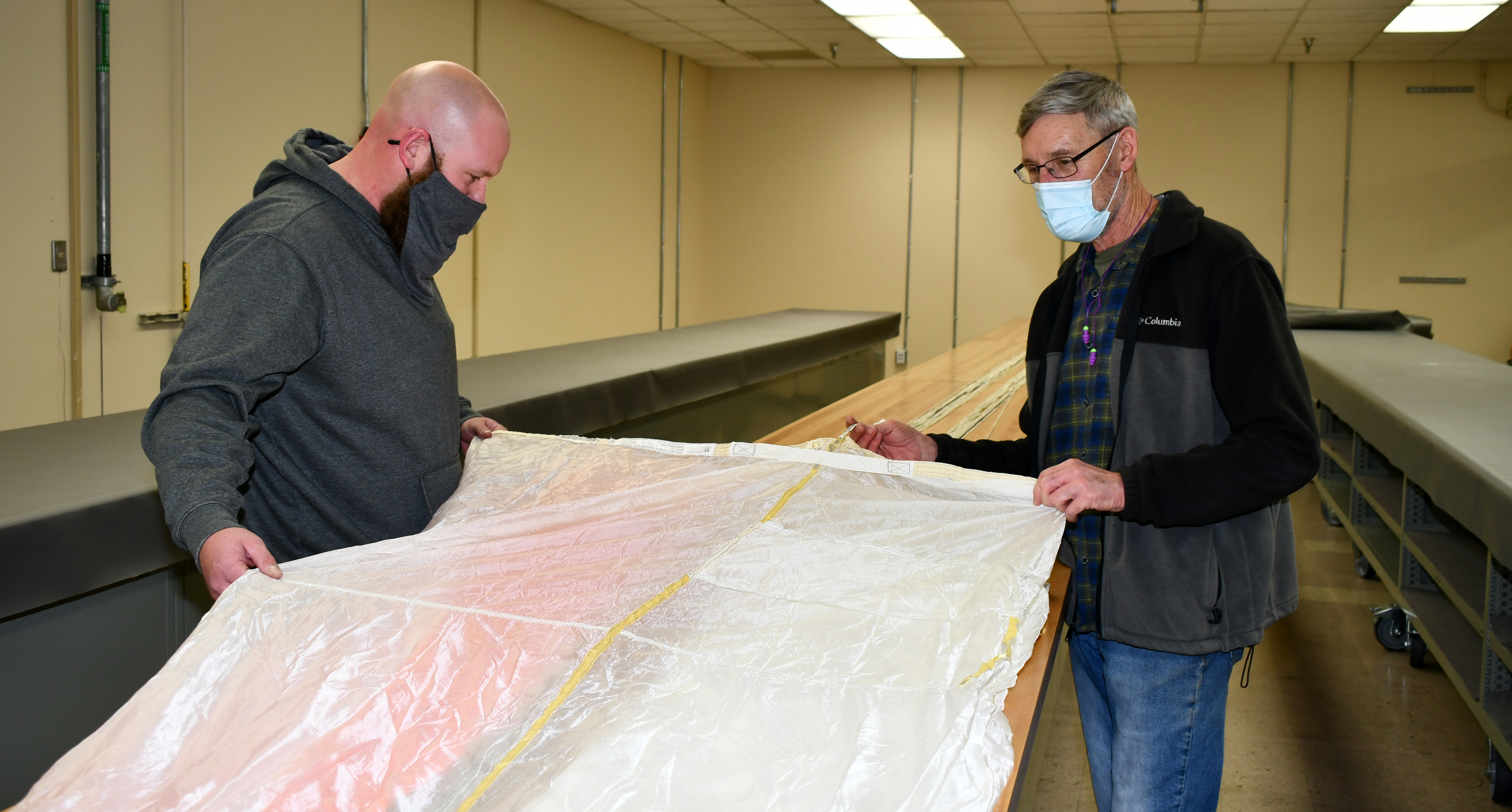 Kristopher Kirksey, a quality assurance specialist at Fleet Readiness Center East (FRCE), and Jeff Ellman, FRCE ordinance and survival shop work leader, inspect an ejection seat parachute for the F-35B Lightning II. FRCE has expanded its support of next-generation naval aviation by declaring capabilities on a new round of F-35 components including these parachutes. 