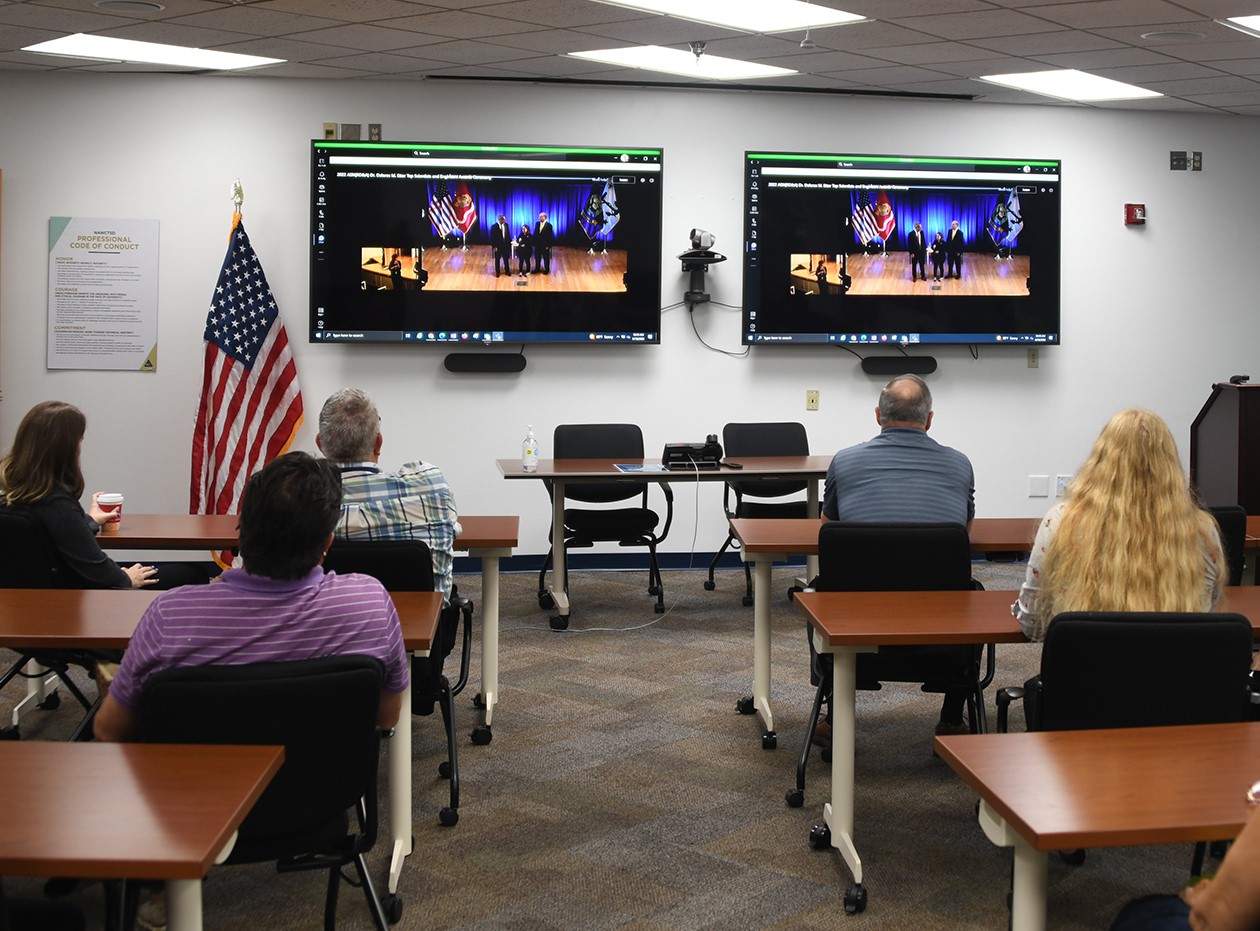 Employees watching ceremony on monitors