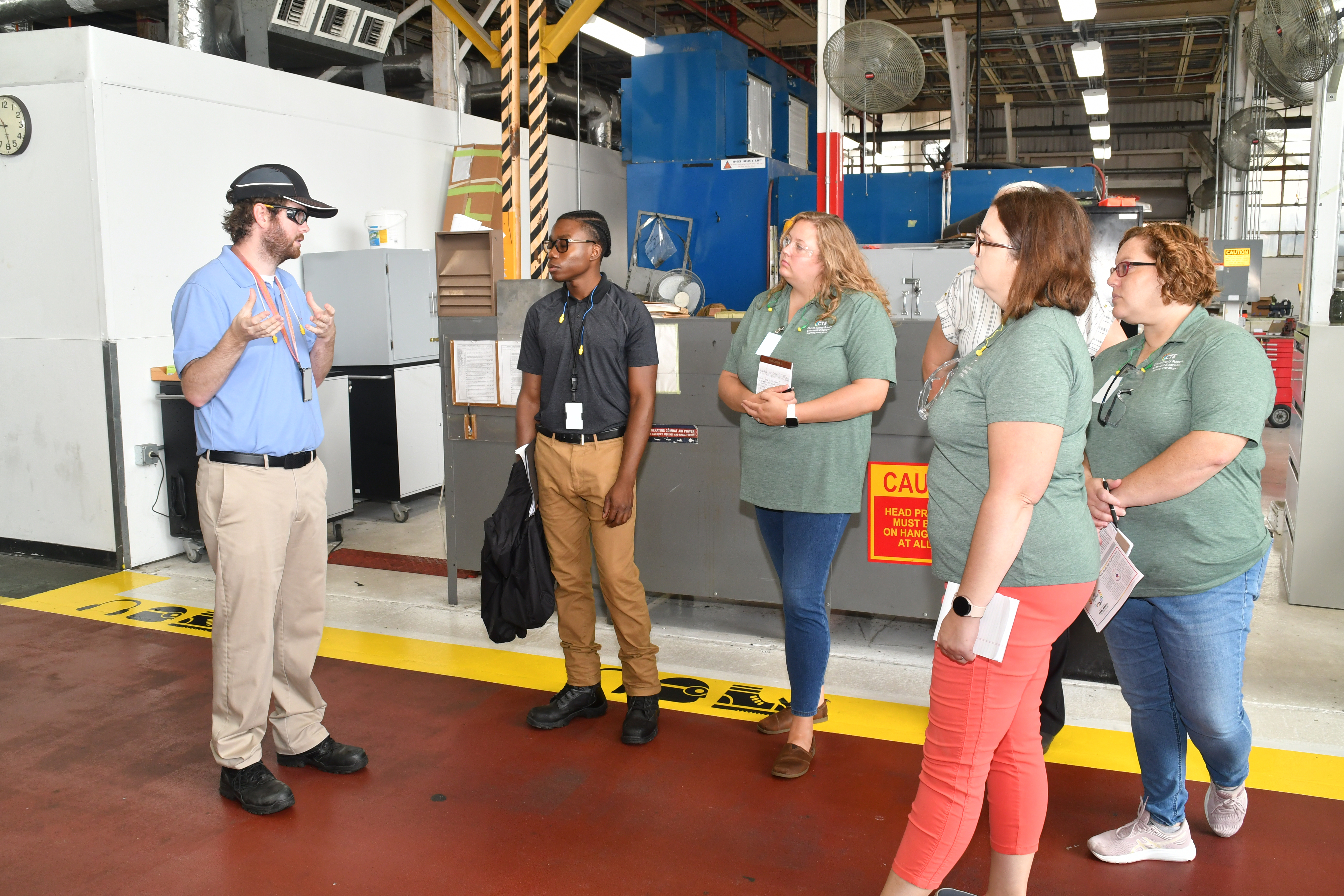 Fleet Readiness Center East (FRCE) Aerospace Engineer Sean Murphy, left, guides a tour of local educators through the depot’s H-53 line during a four day externship program focused on preparing students for careers in industry.