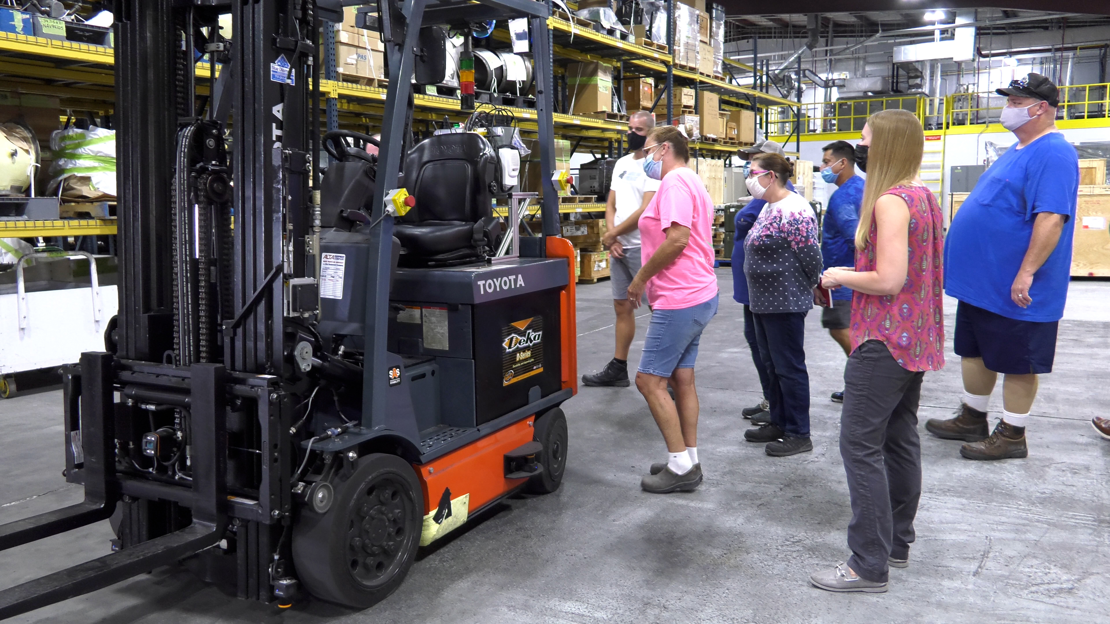 Employees observe self-driving forklift