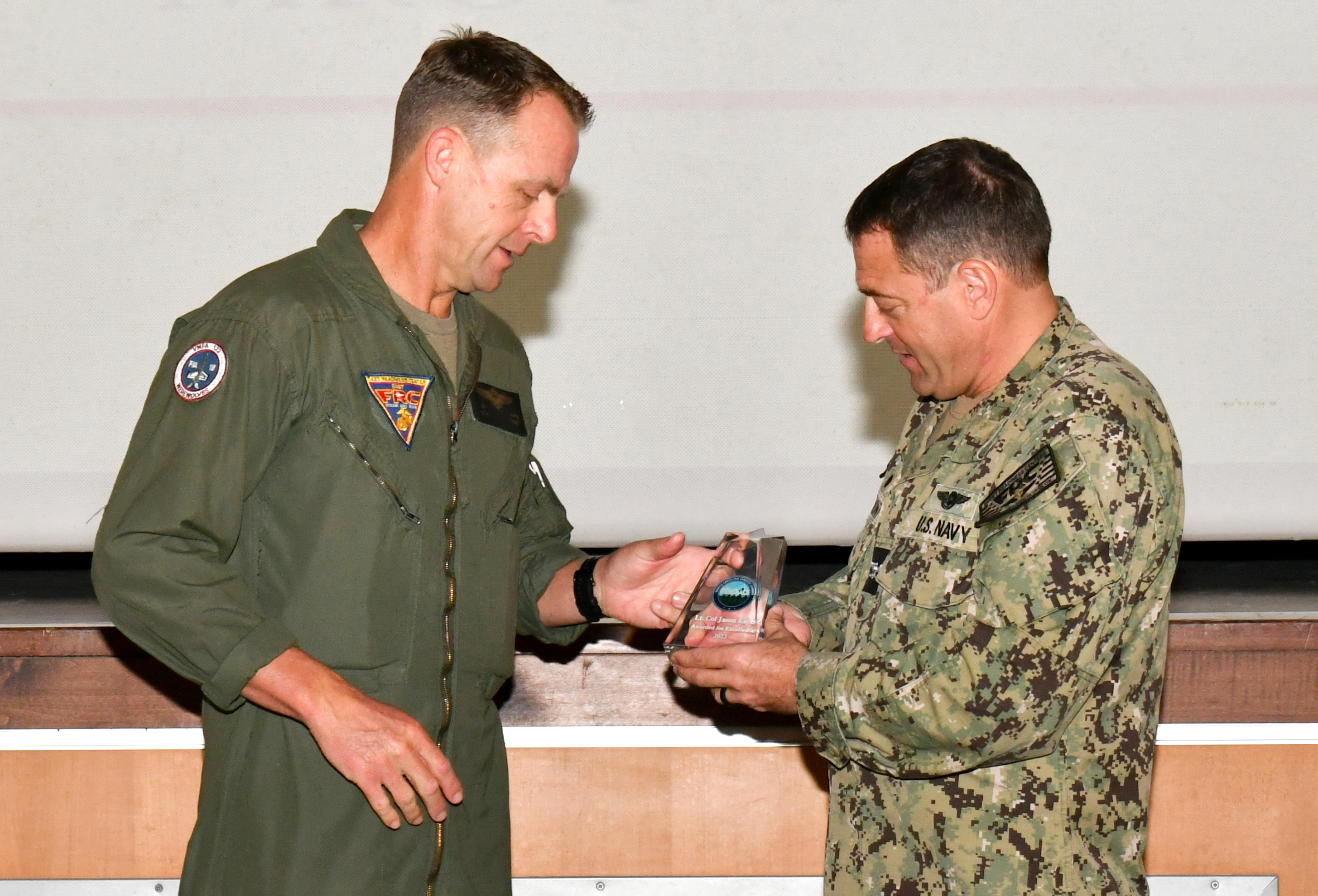 Navy captain passes award statuette to Marine lieutenant colonel