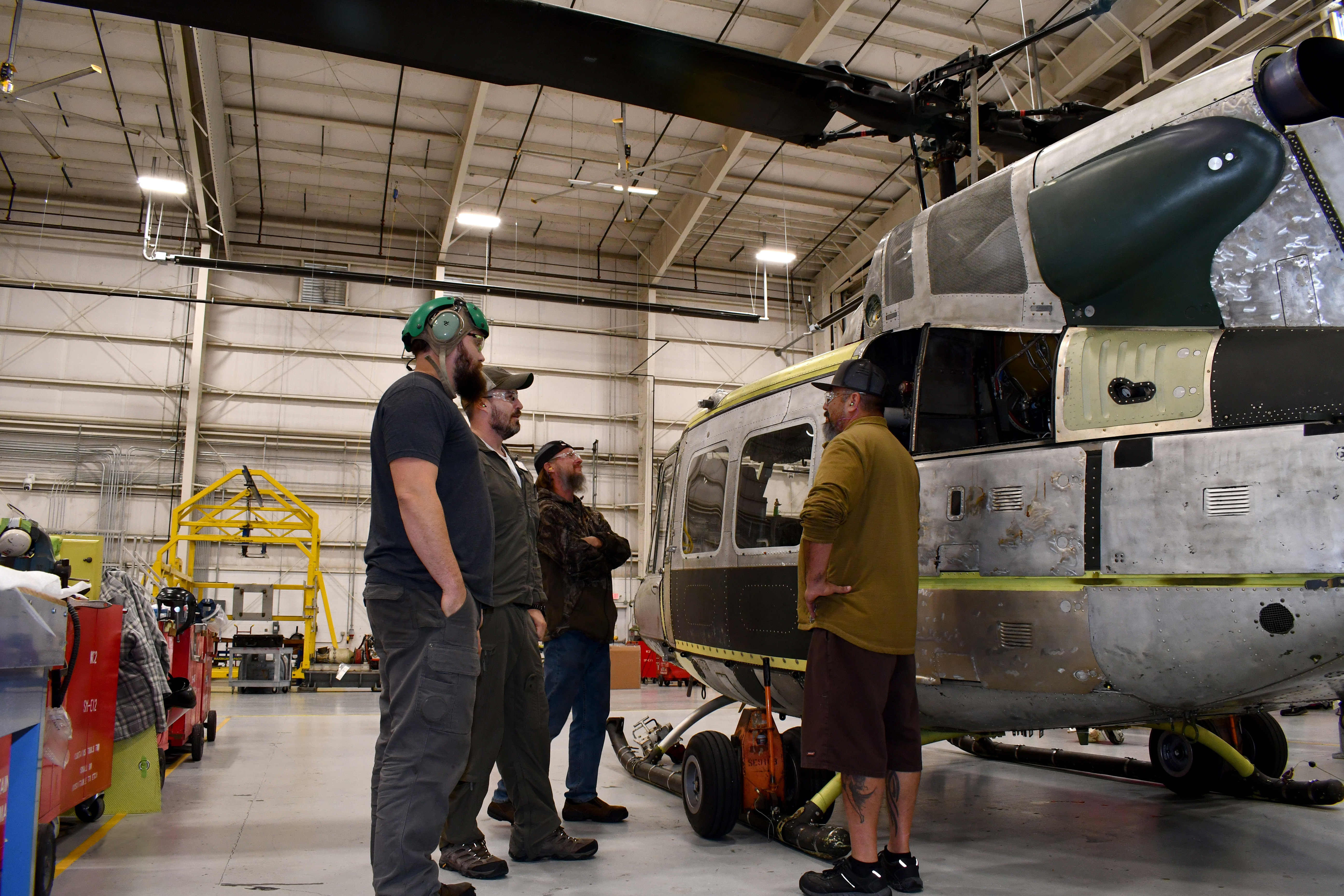 UH-1N helicopter maintainers and pilot discuss aircraft in hangar