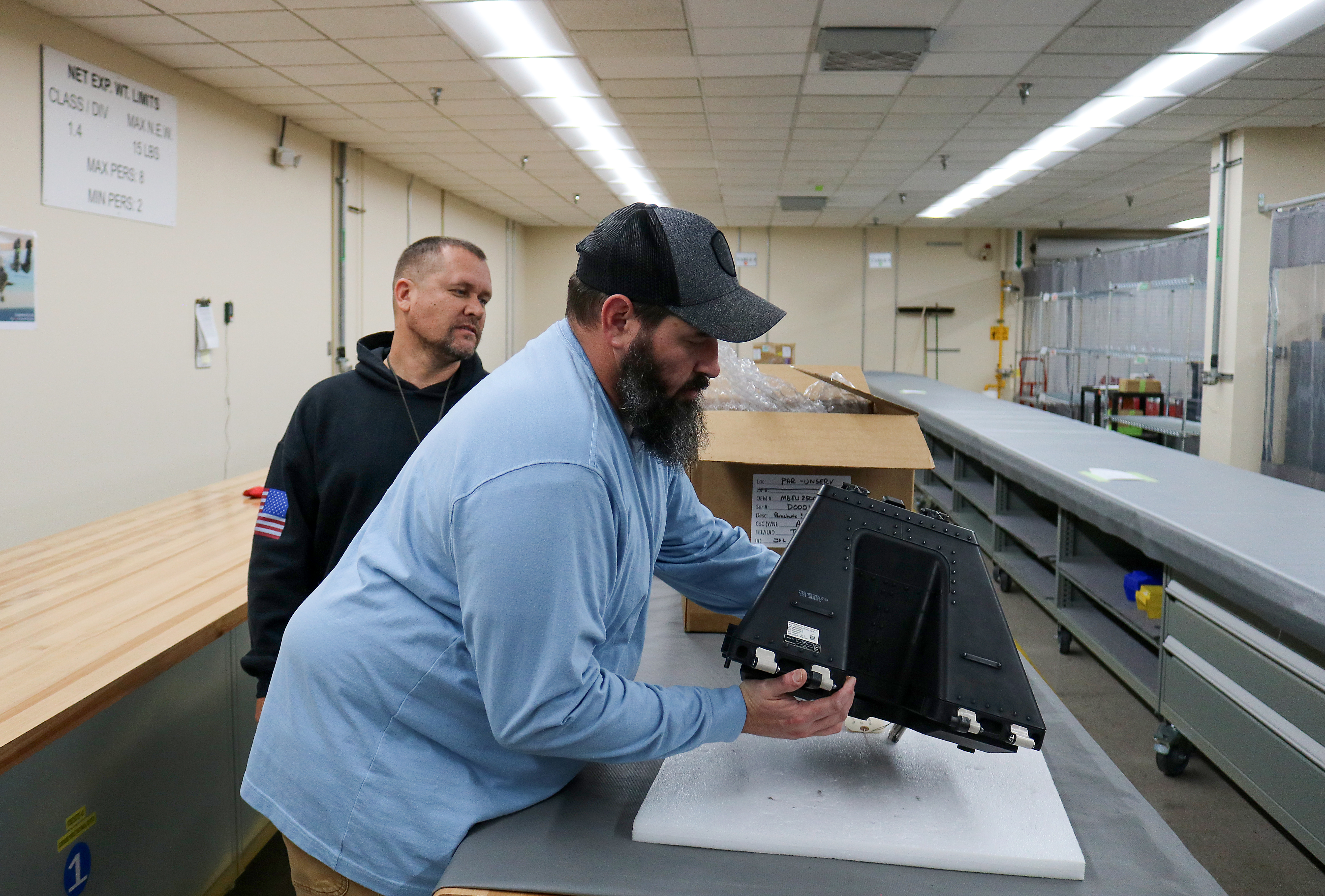 Eric Gares, front, oxygen equipment repair mechanic, and quality assurance inspector Josh Unruh put the final touches on the 100th F-35 Lightning II parachute repacked at Fleet Readiness Center East (FRCE). FRCE achieved this milestone less than one year after inducting their first F-35 parachute. Since 2018, the depot had declared capability on 32 components, including the parachutes for the fifth-generation fighter. 