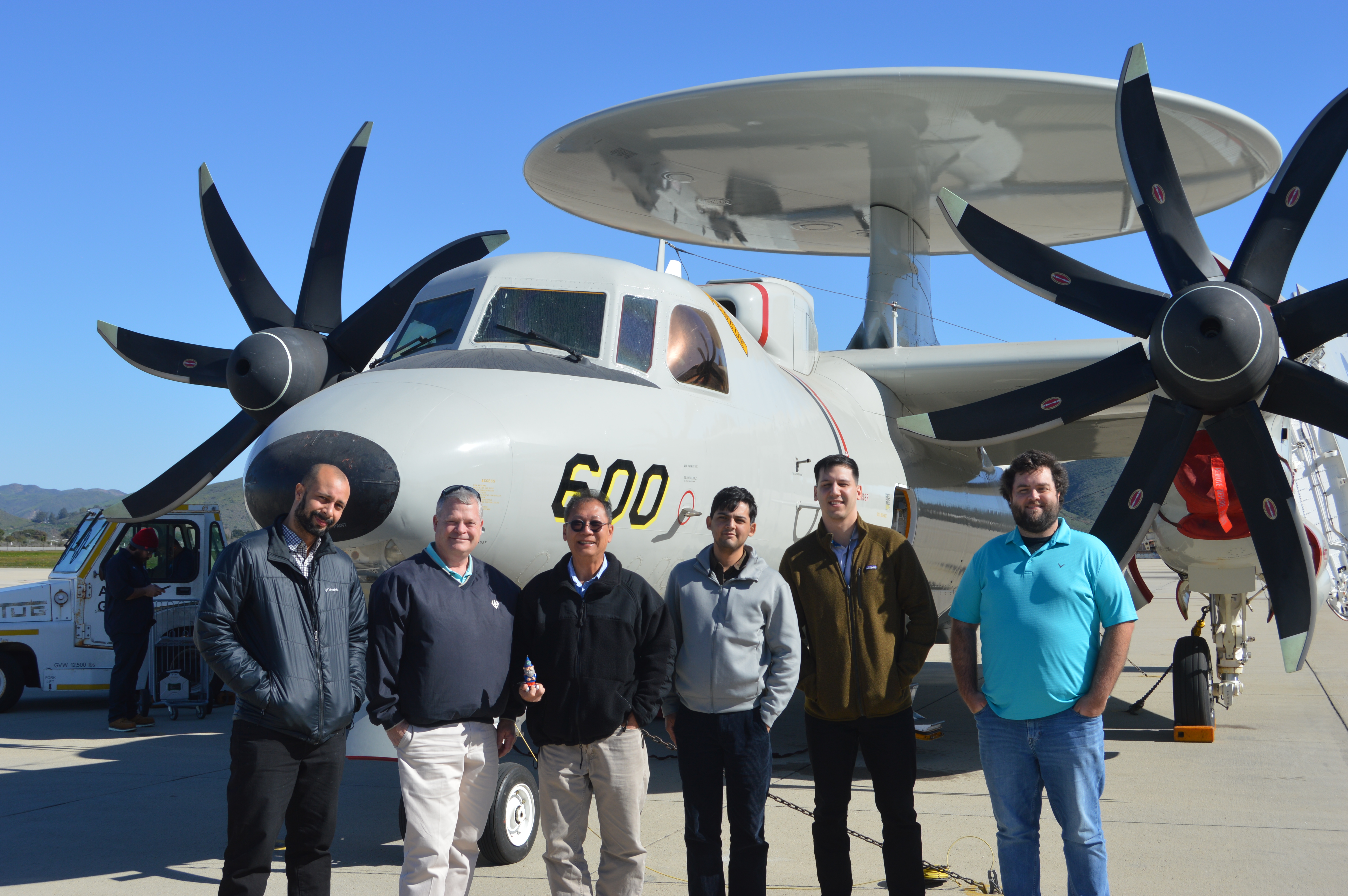 Group of people standing in front of E-2D aircraft.