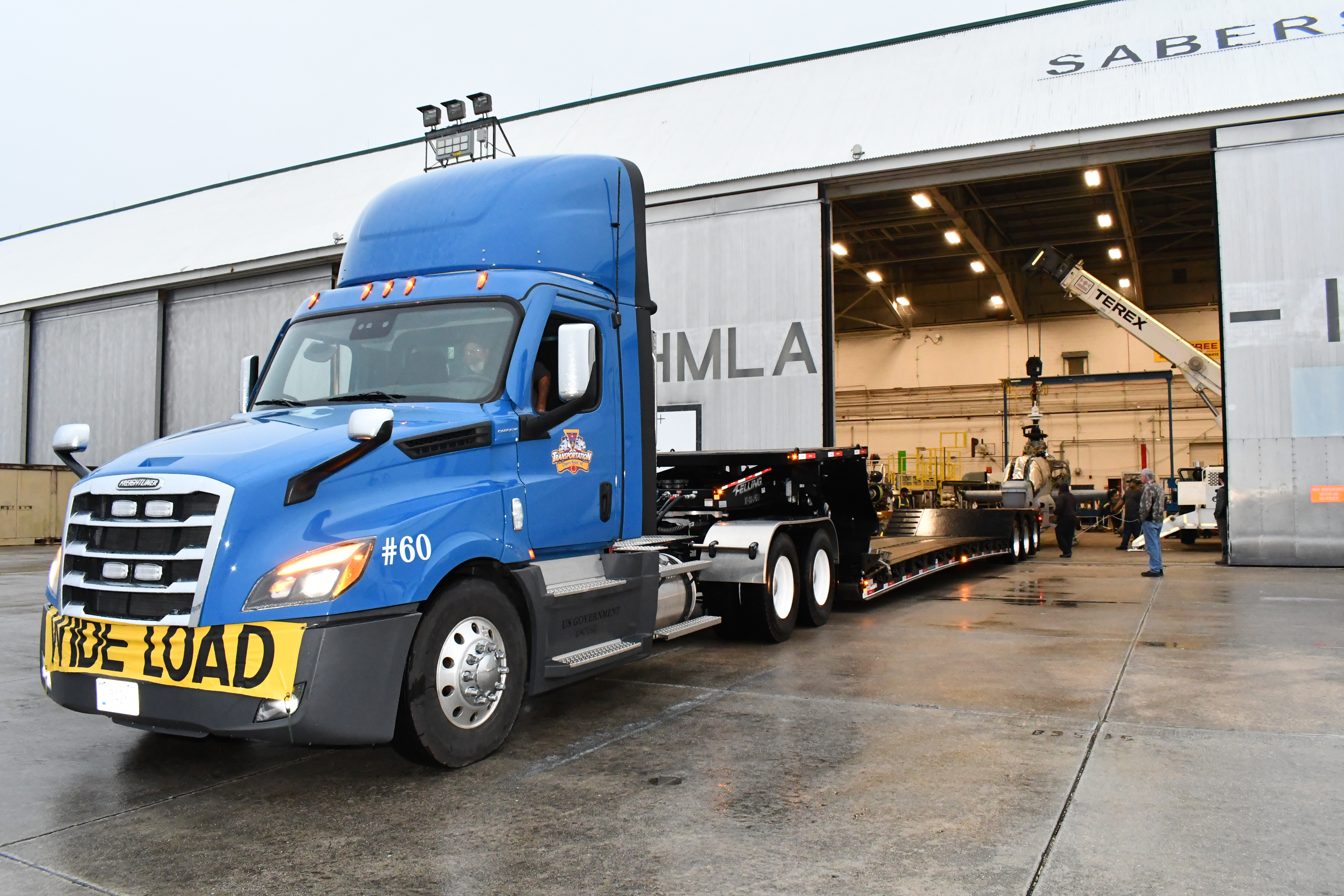 Truck with double-drop trailer backs into aircraft hangar