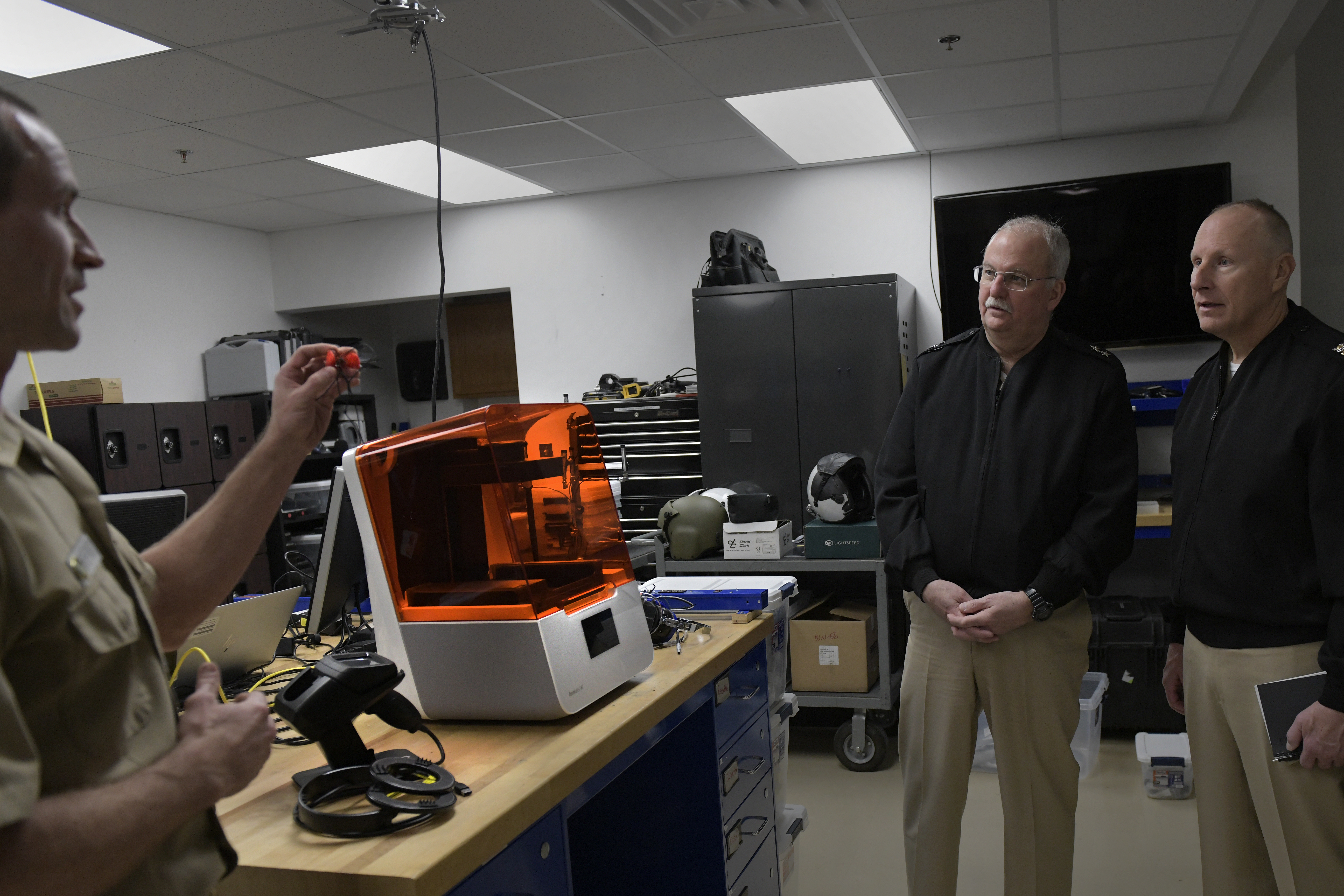 A naval officer demonstrates a process to use 3D printers and a digital scanner to produce custom ear plugs.