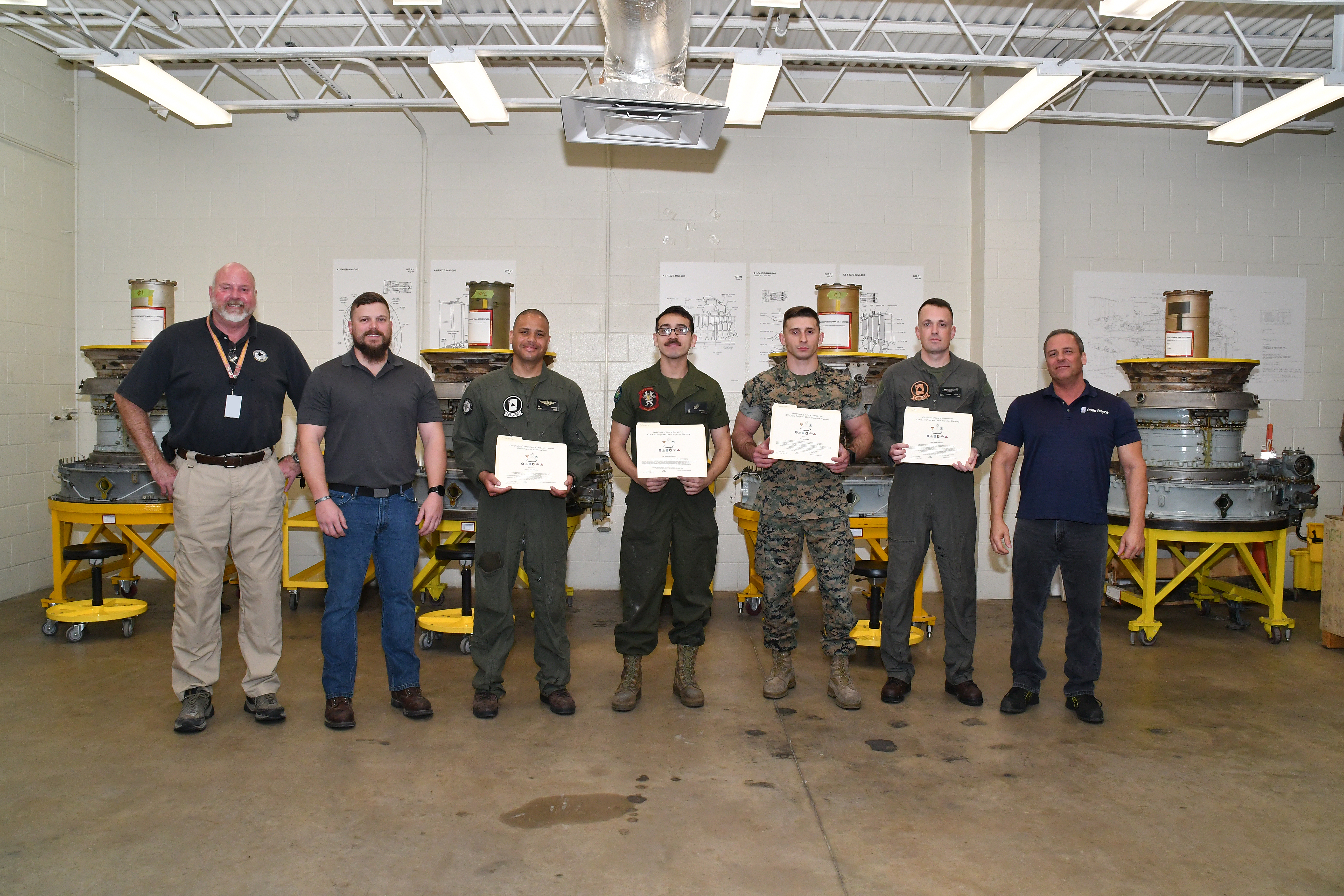 Terry Gerber, AV-8B Remote Visual Inspection (RVI) Program developer and manager, left, poses with graduates of the F402 Engine Tier 6 Inspector Rating certification course, Mar. 13, 2023. Launched in October of last year, this is the most recent course offered through the Fleet Readiness Center East’s AV-8B RVI program which trains and certifies Marines maintaining the AV-8B Harrier to successfully perform digital borescope processes on the Harrier’s F402 engine.