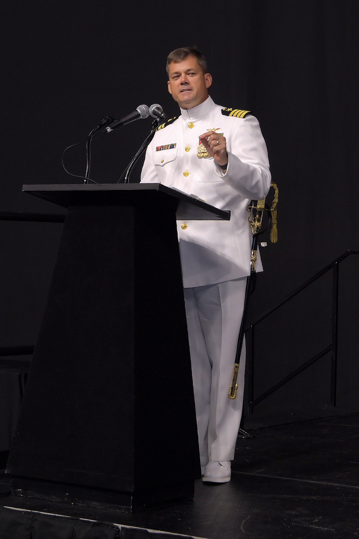 Navy officer speaking at podium.