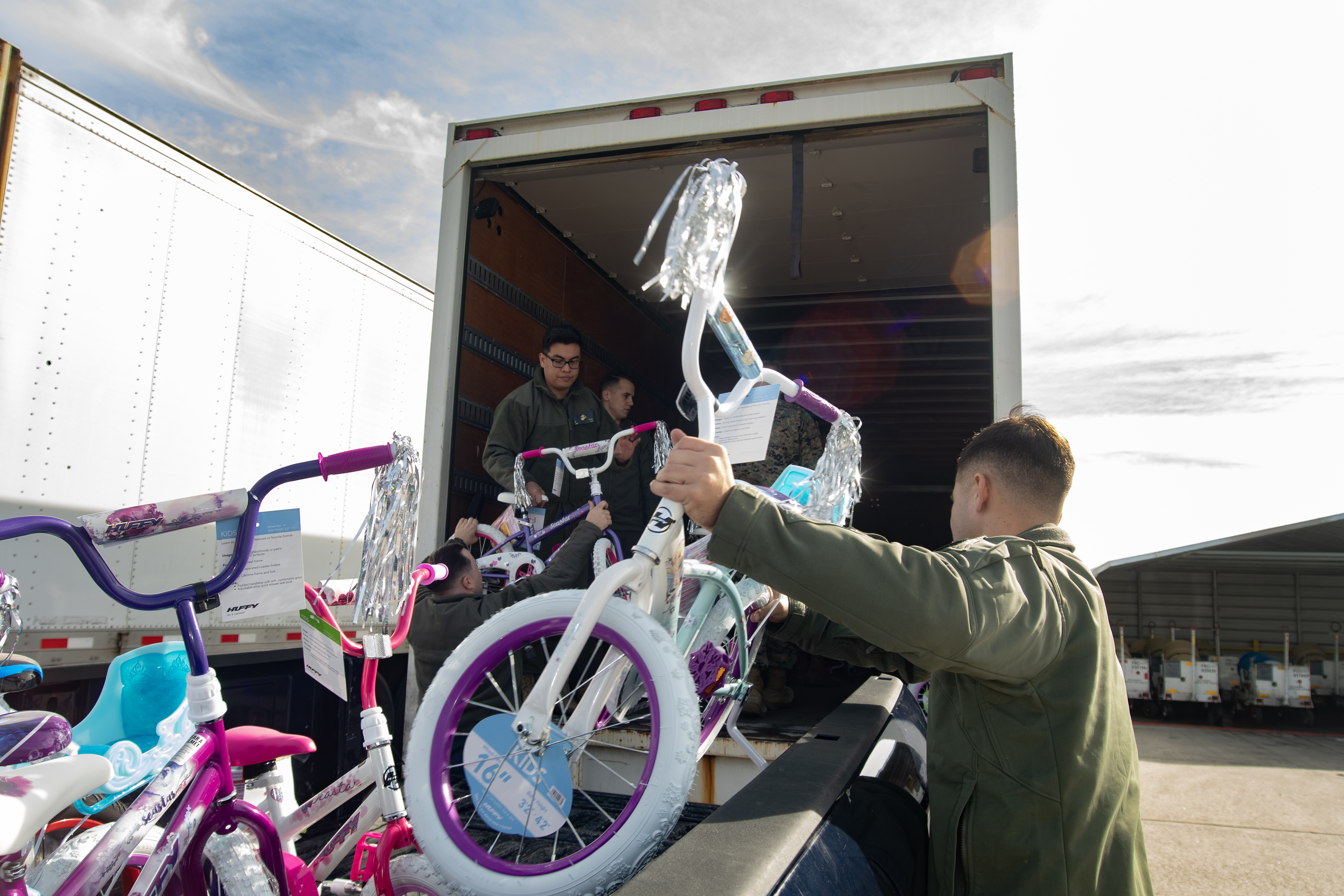 Man on right grabbing a children's bike to put into semi-trailer 