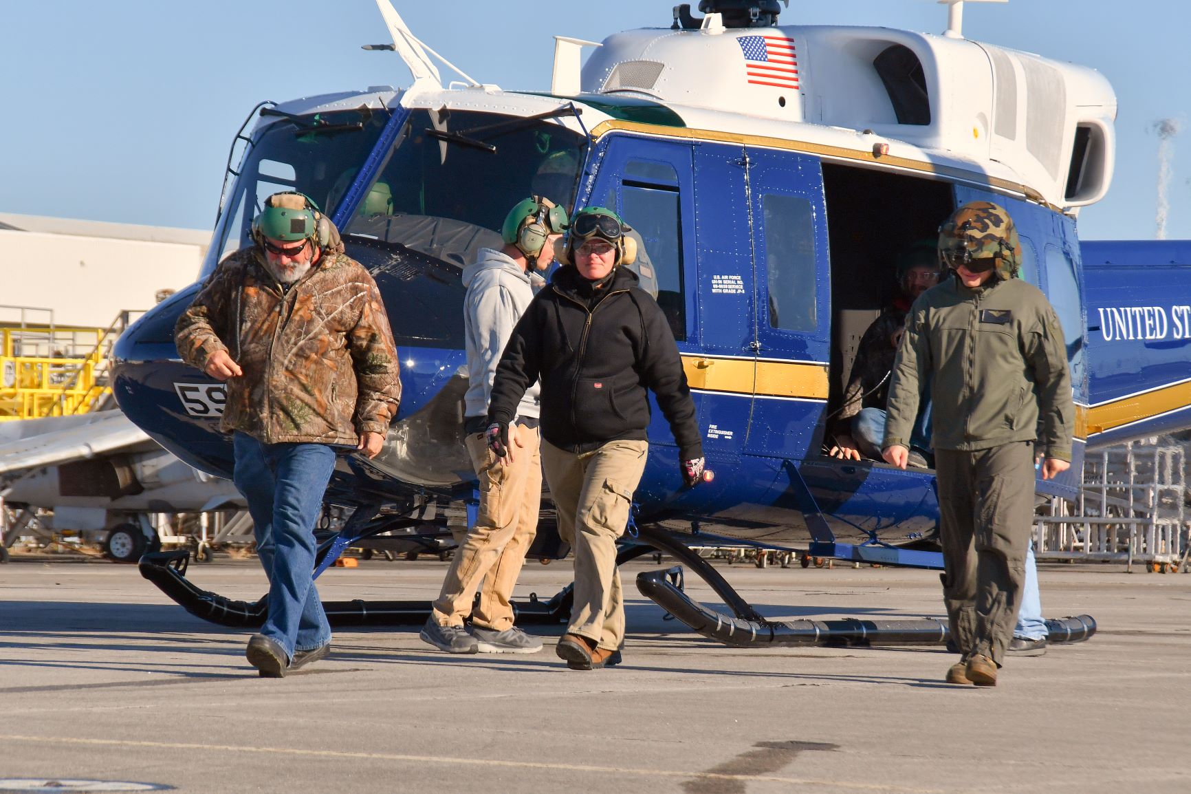 Marine and civilian ground walk in front of Air Force UH-1N helicopter following functional check flight 