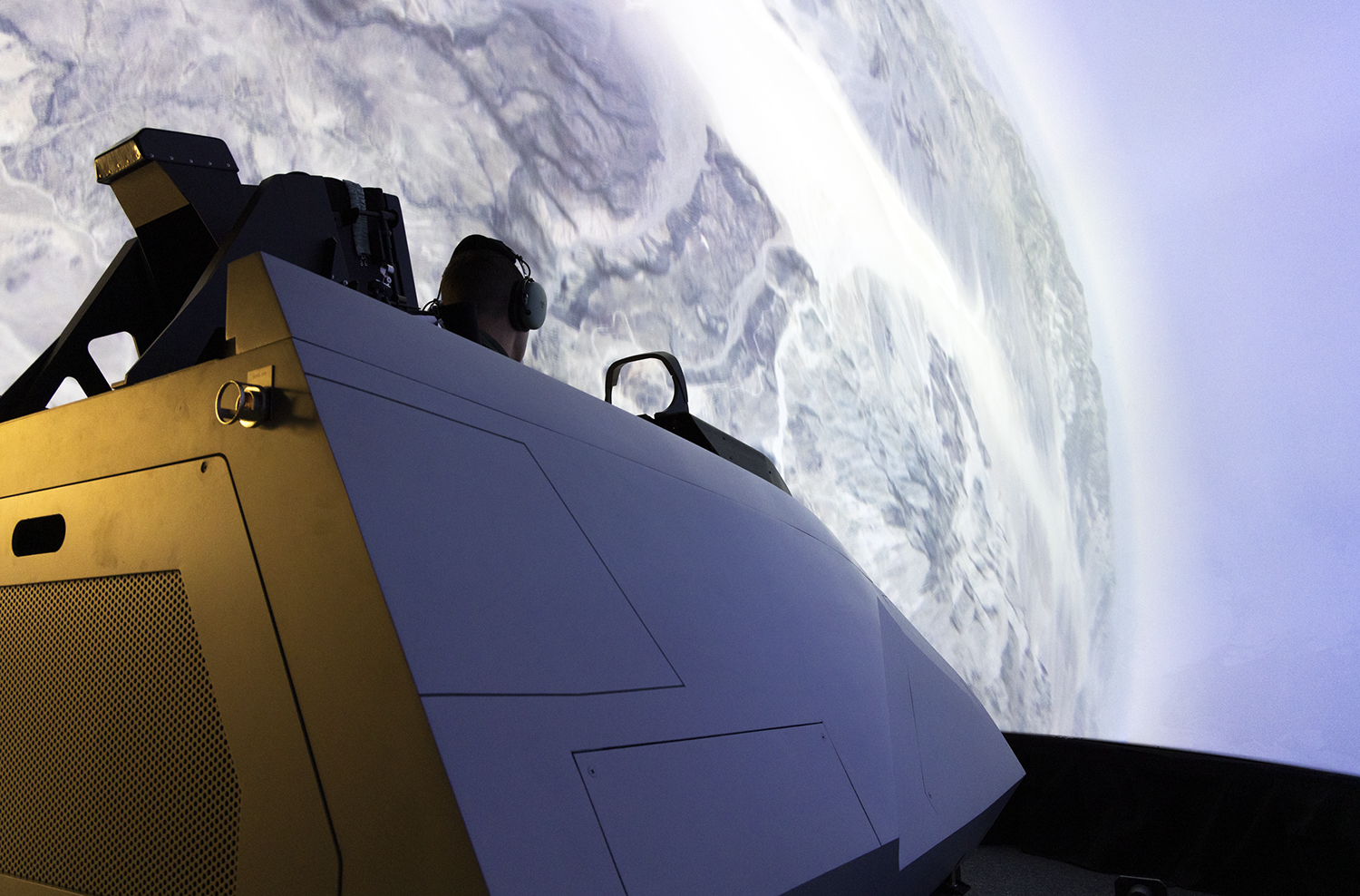 A cockpit sits in a domed simulator that with a global display.