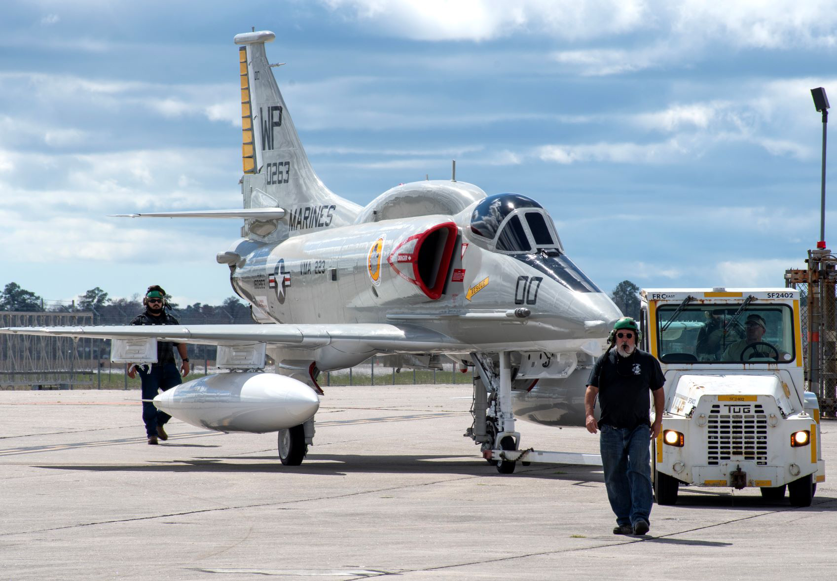 Man walking in front of aircraft and small metal vehicle 