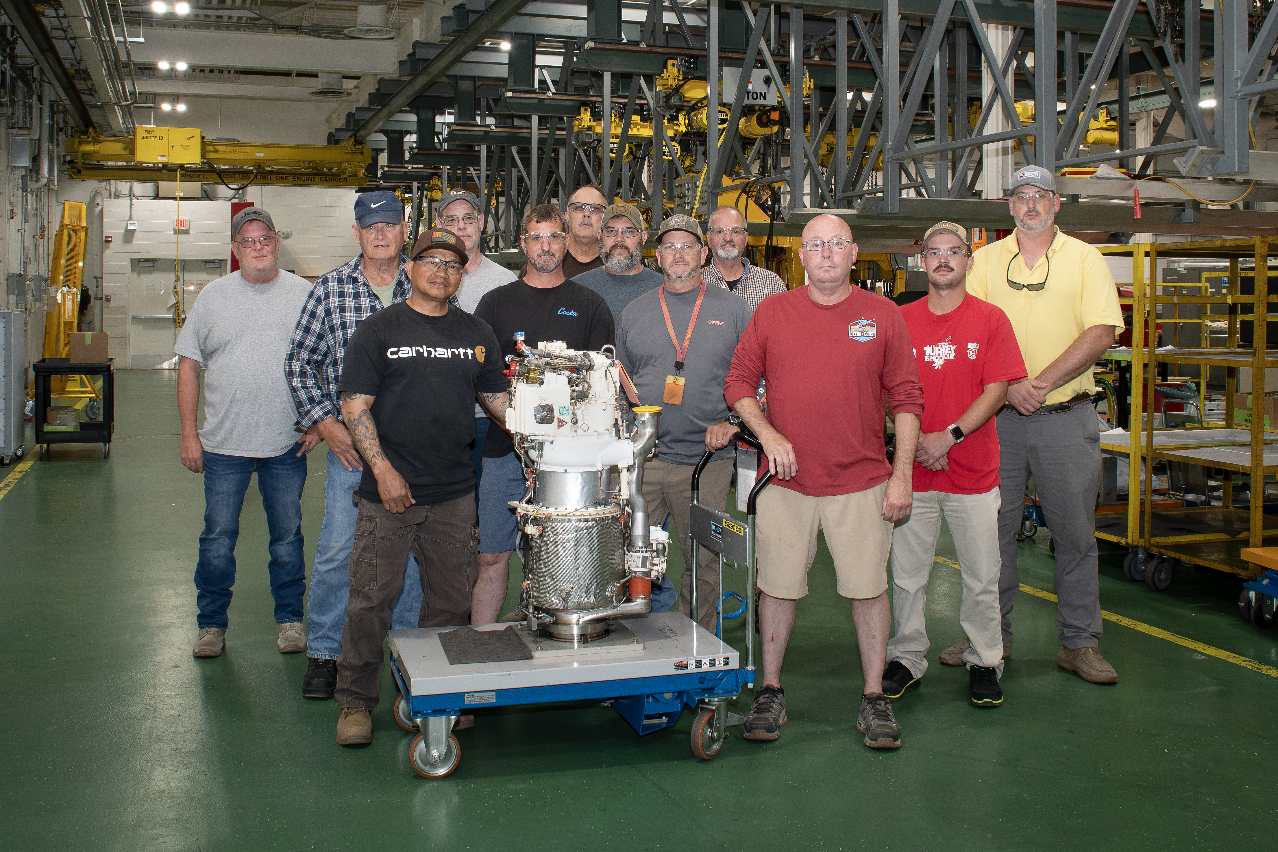 Artisans at Fleet Readiness Center East’s (FRCE) Engine Driven Compressor and Gas Turbine shop stand for a group photo with a freshly overhauled auxiliary power unit for the F/A-18E/F Super Hornet. FRCE recently achieved a significant production milestone by eliminating high-priority backorders for auxiliary power units used in the Super Hornet, bolstering the platform’s mission readiness. 