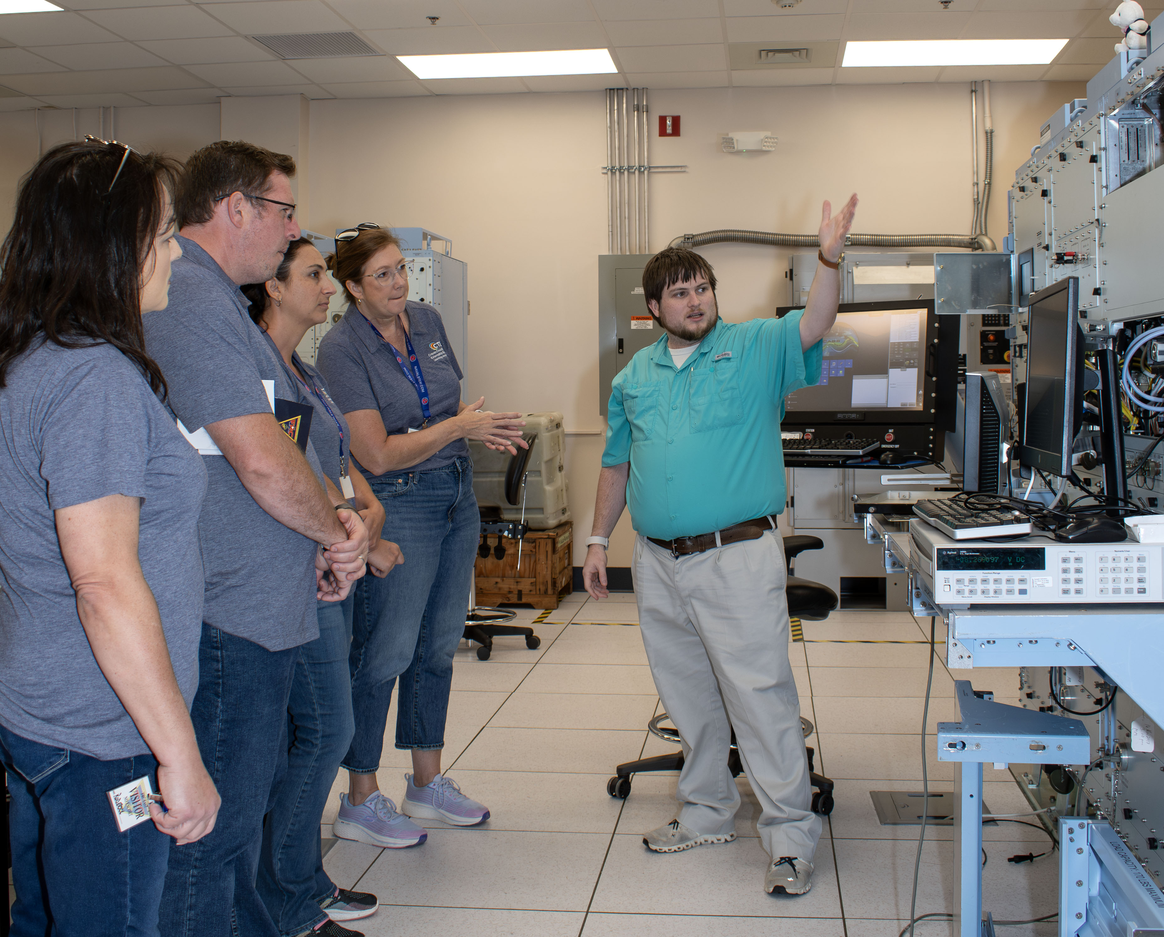 Five people standing with one showing the others a machine