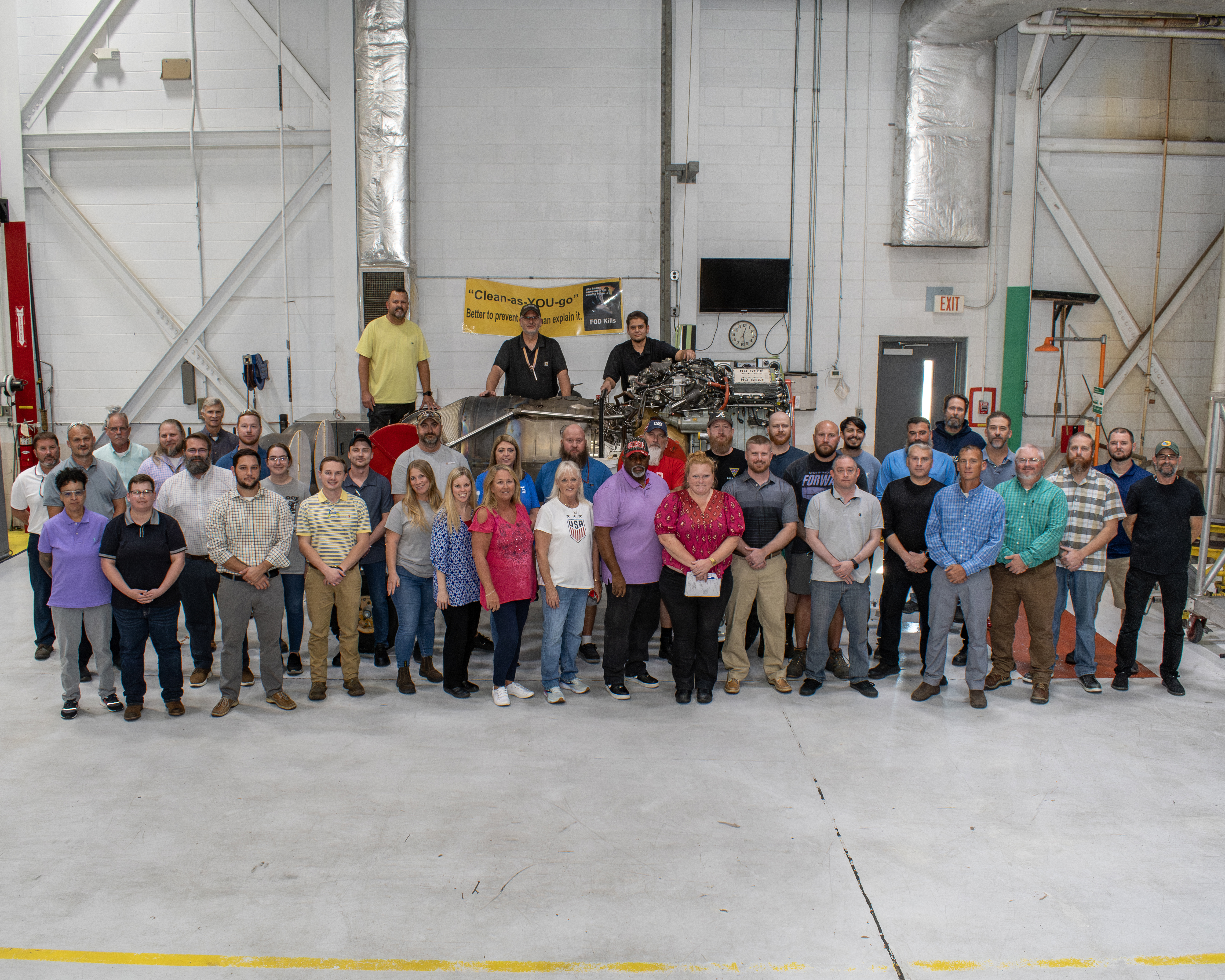 Group of people stand in front of aircraft engine 