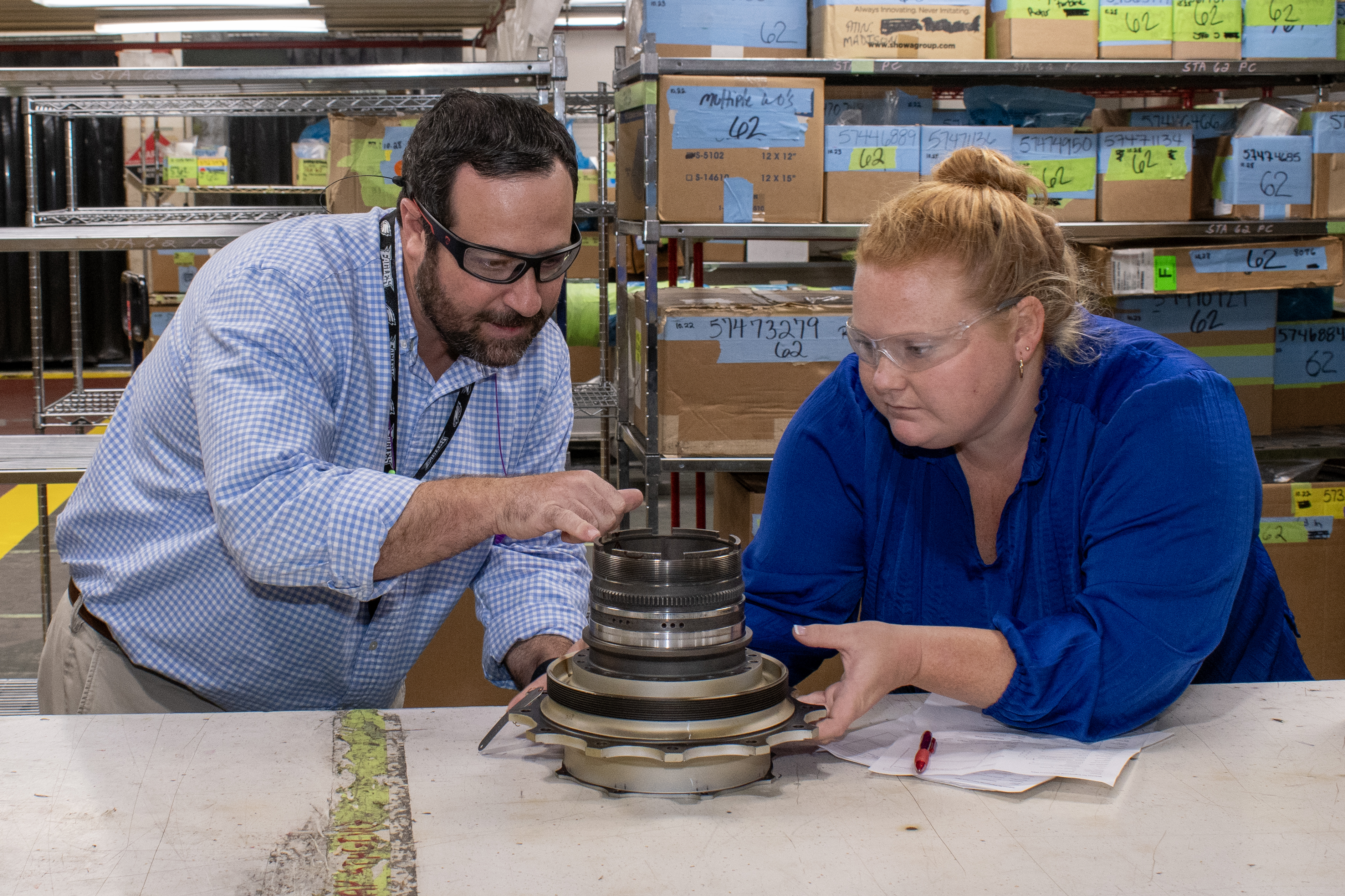 man and woman inspect mechanical part 