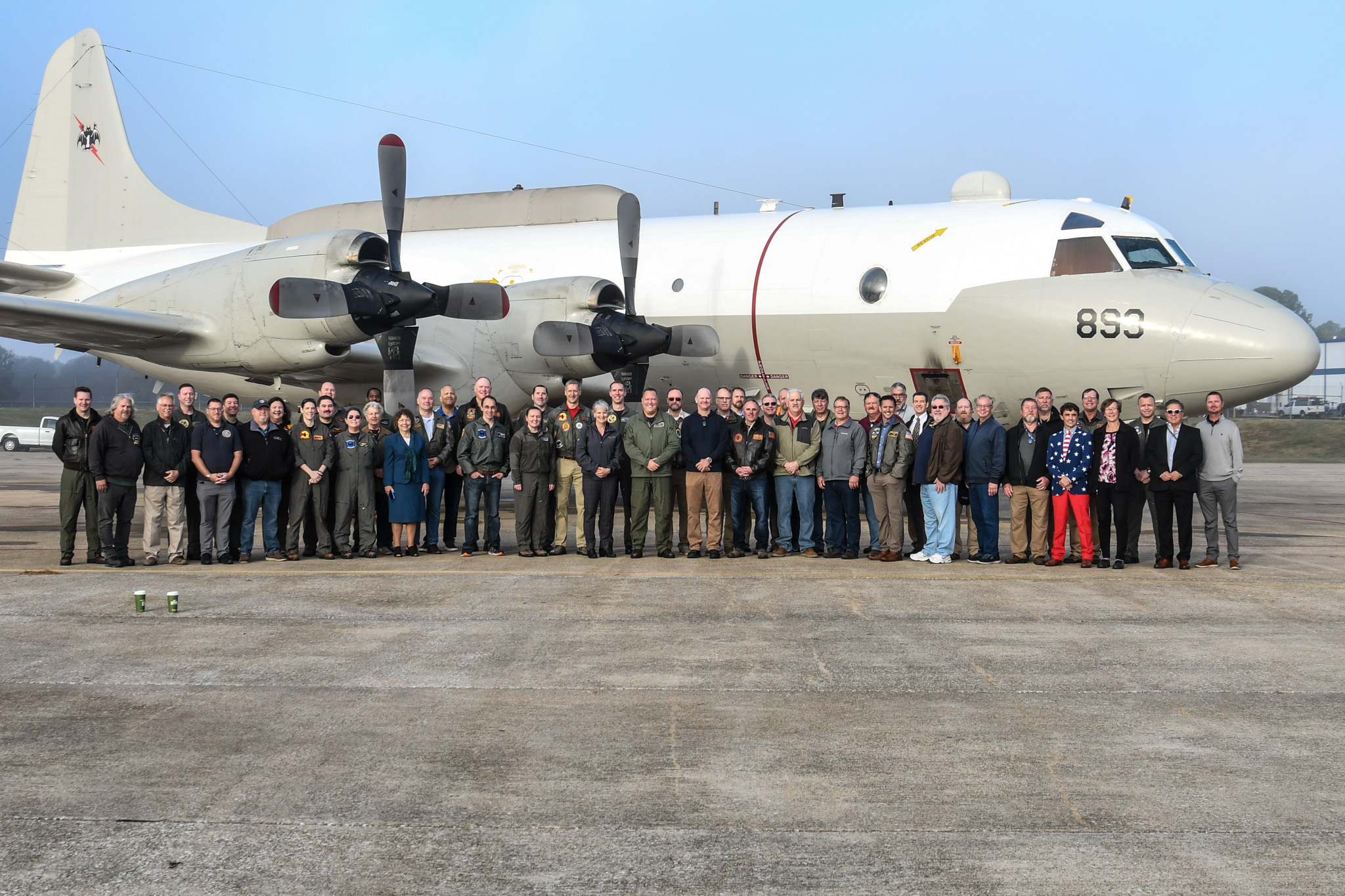 Group of people standing in front of a plane on a tarmac