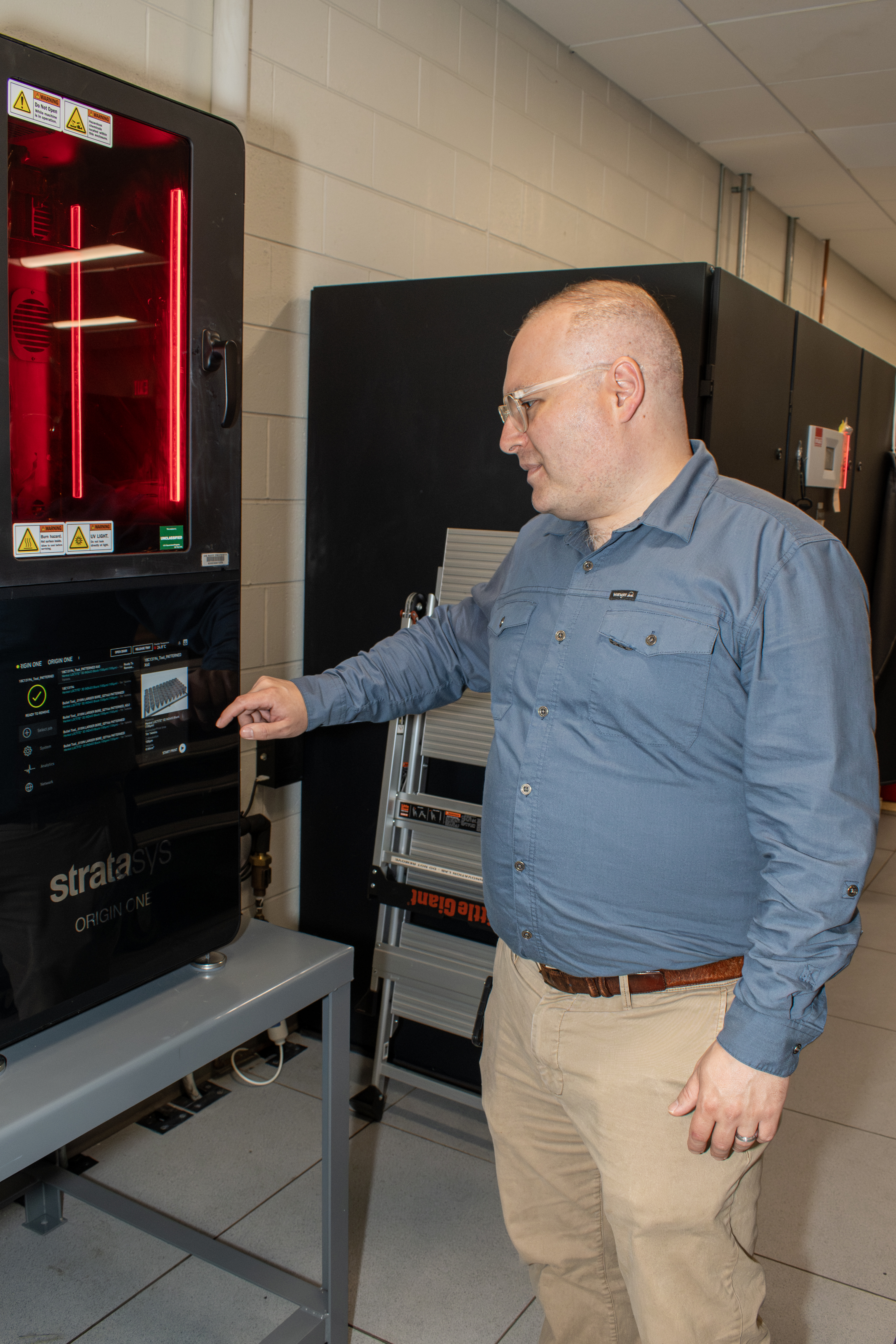 Engineer prepares to push button on front control panel of digital light processing 3D printer